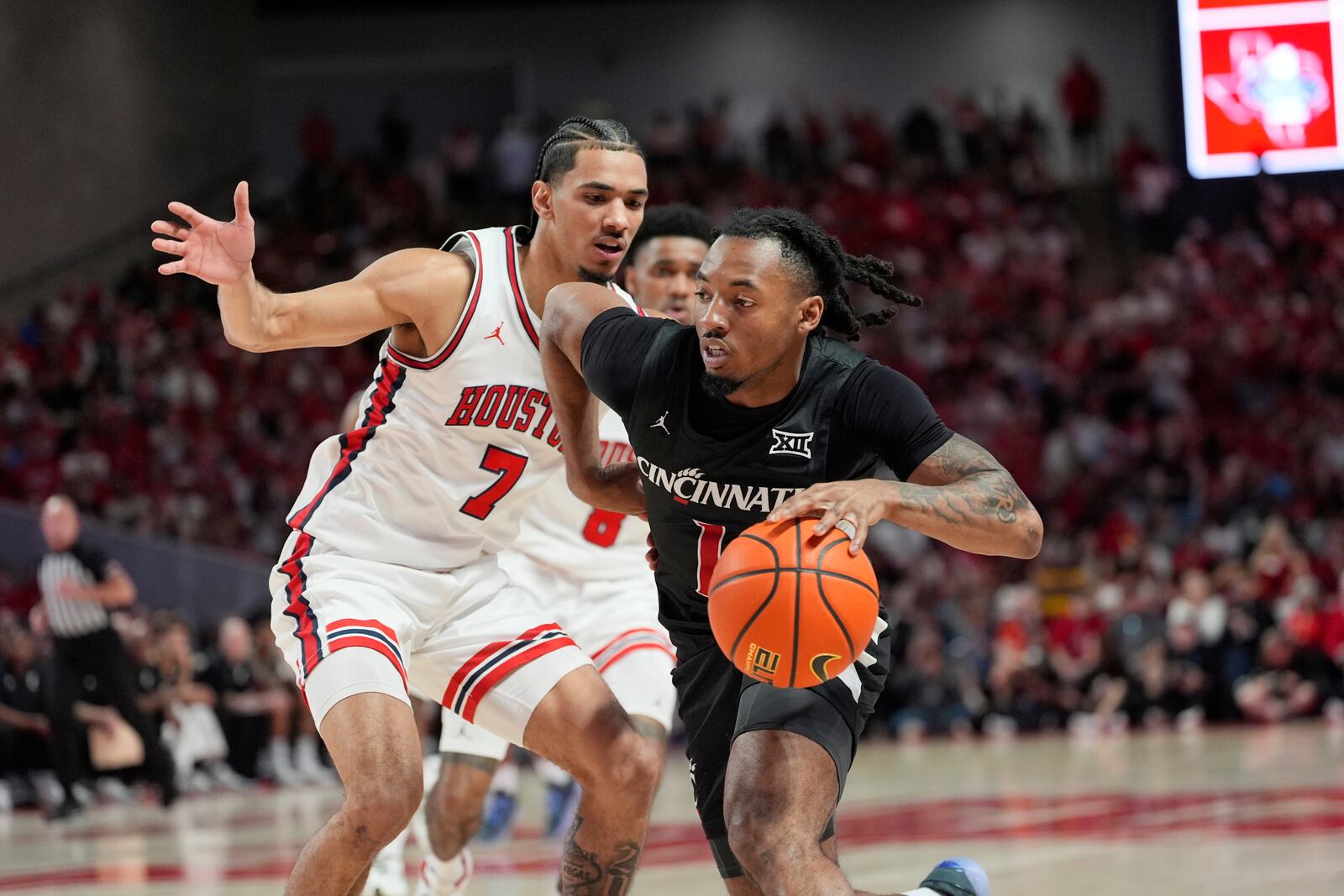 Cincinnati's Day Day Thomas (1) drives past Houston's Milos Uzan (7) during the first half of an NCAA college basketball game Saturday, March 1, 2025, in Houston. (AP Photo/David J. Phillip)