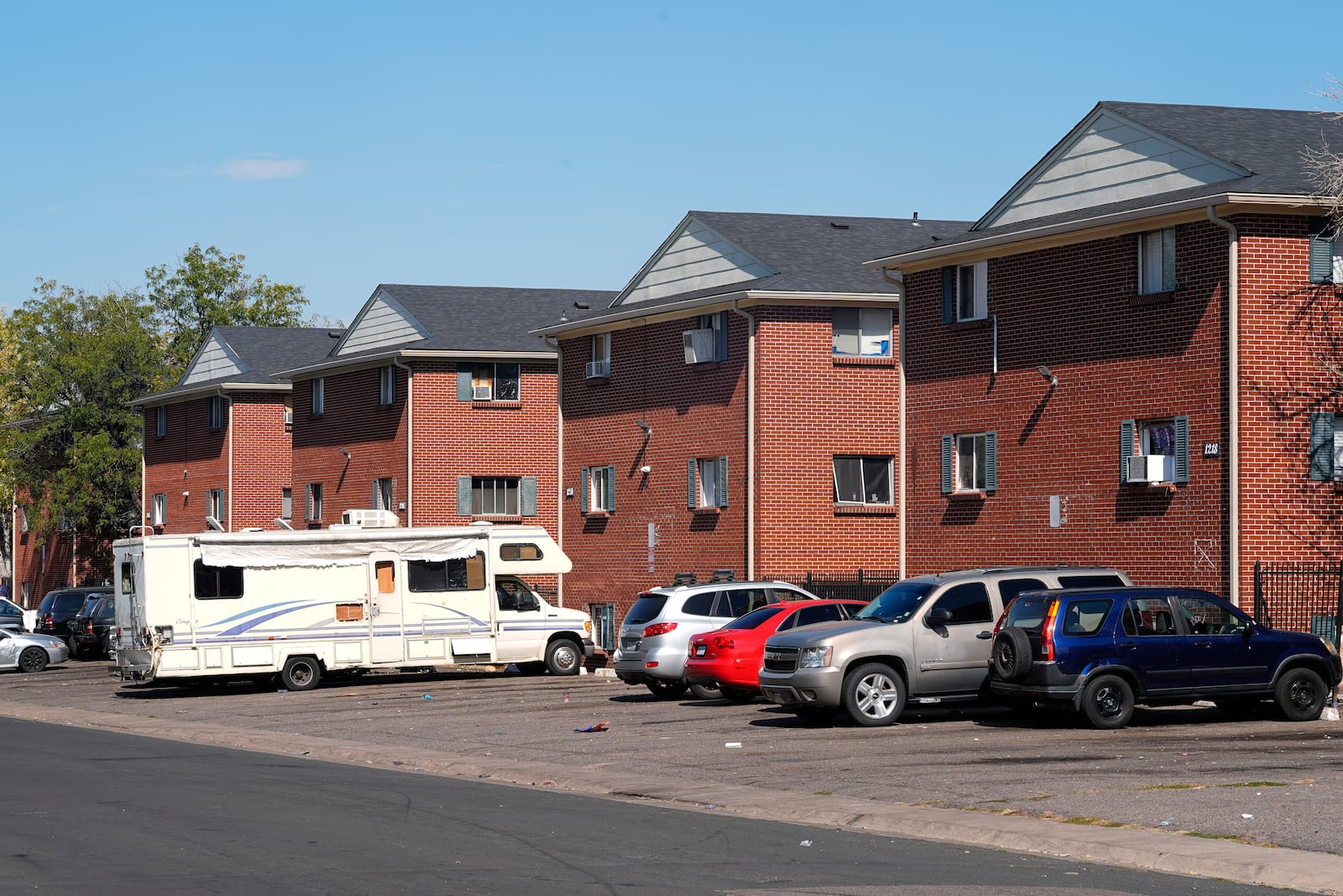 Residents' vehicles sit outside a row of apartment houses occupied by Venezuelans who have migrated to the United States, Wednesday, Oct. 9, 2024, in the east Denver suburb of Aurora, Colo. (AP Photo/David Zalubowski)