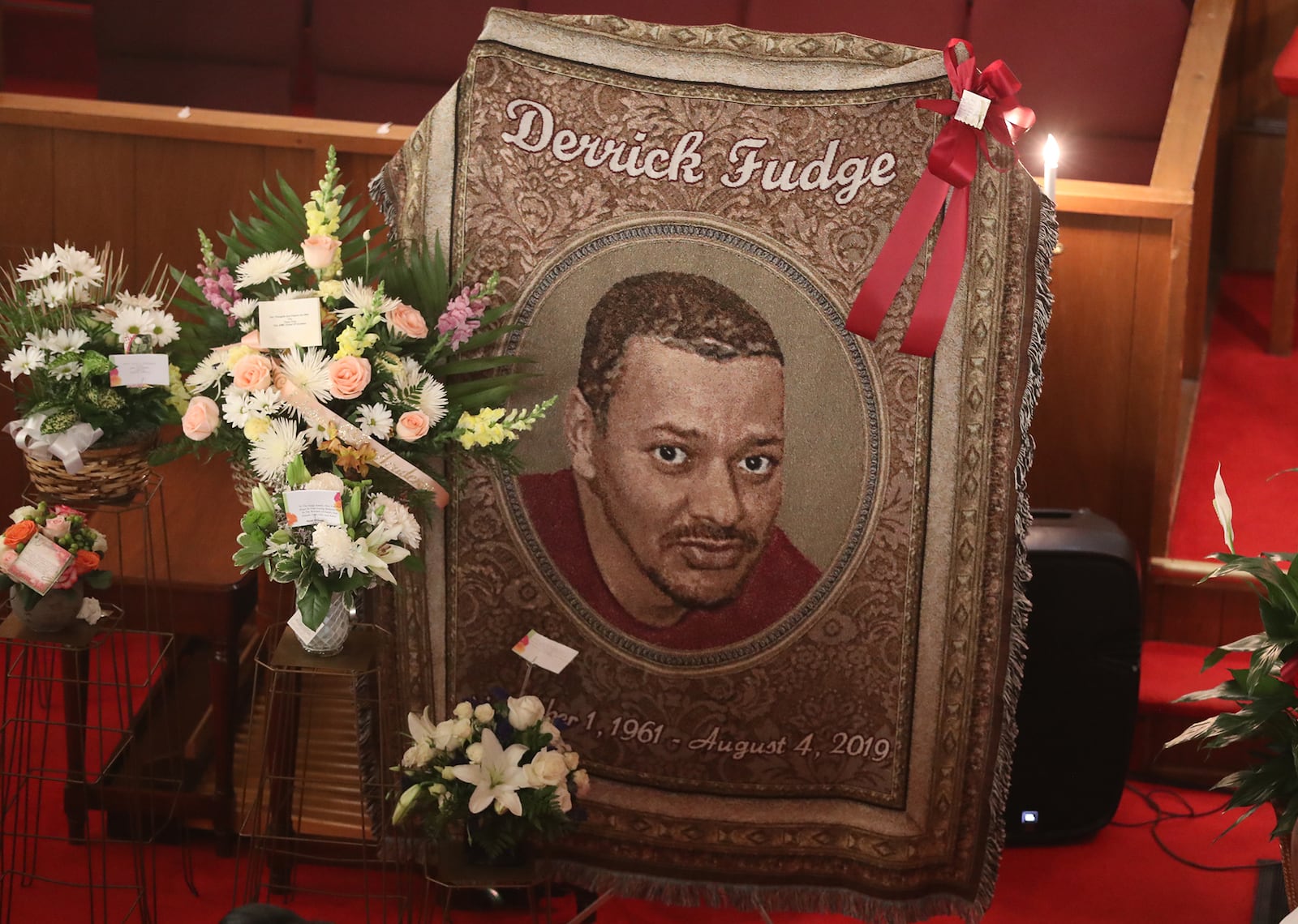 A tapestry with Derrick Fudge's picture hangs next to Fudge's casket Saturday during his funeral service at St. John Missionary Baptist Church. BILL LACKEY/STAFF