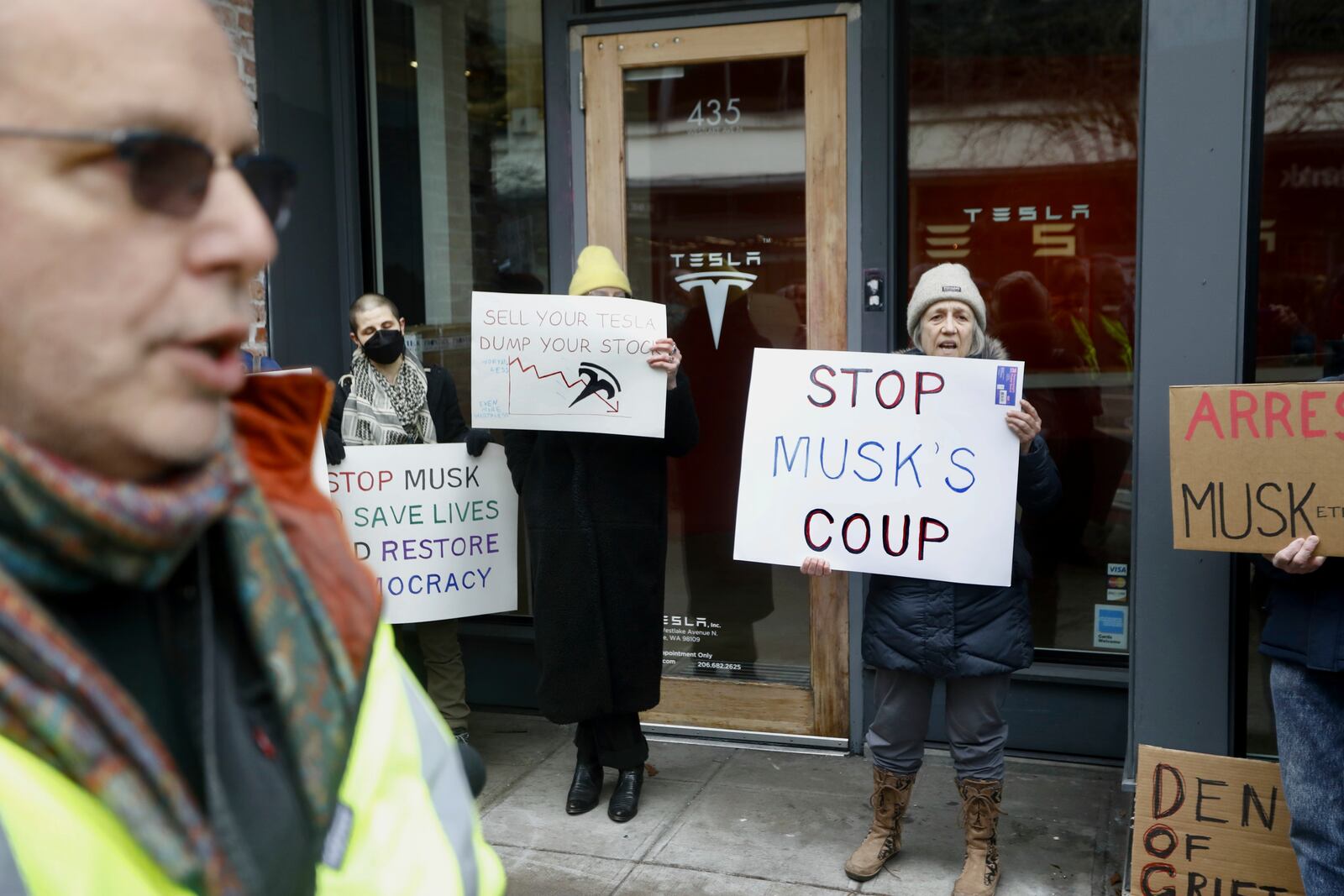 People protesting Elon Musk's actions in the Trump administration hold signs outside a Tesla showroom in Seattle on Thursday, Feb. 13, 2025. (AP Photo/Manuel Valdes)