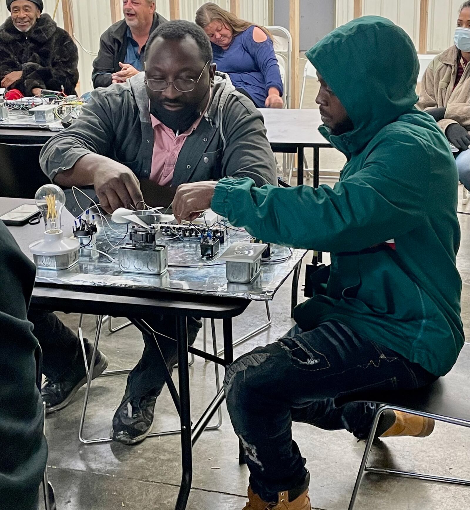 Trade program graduates Derrick Hagger, left, and Brandon Johnson explain the functions of an HVAC control system prototype. AIMEE HANCOCK / STAFF