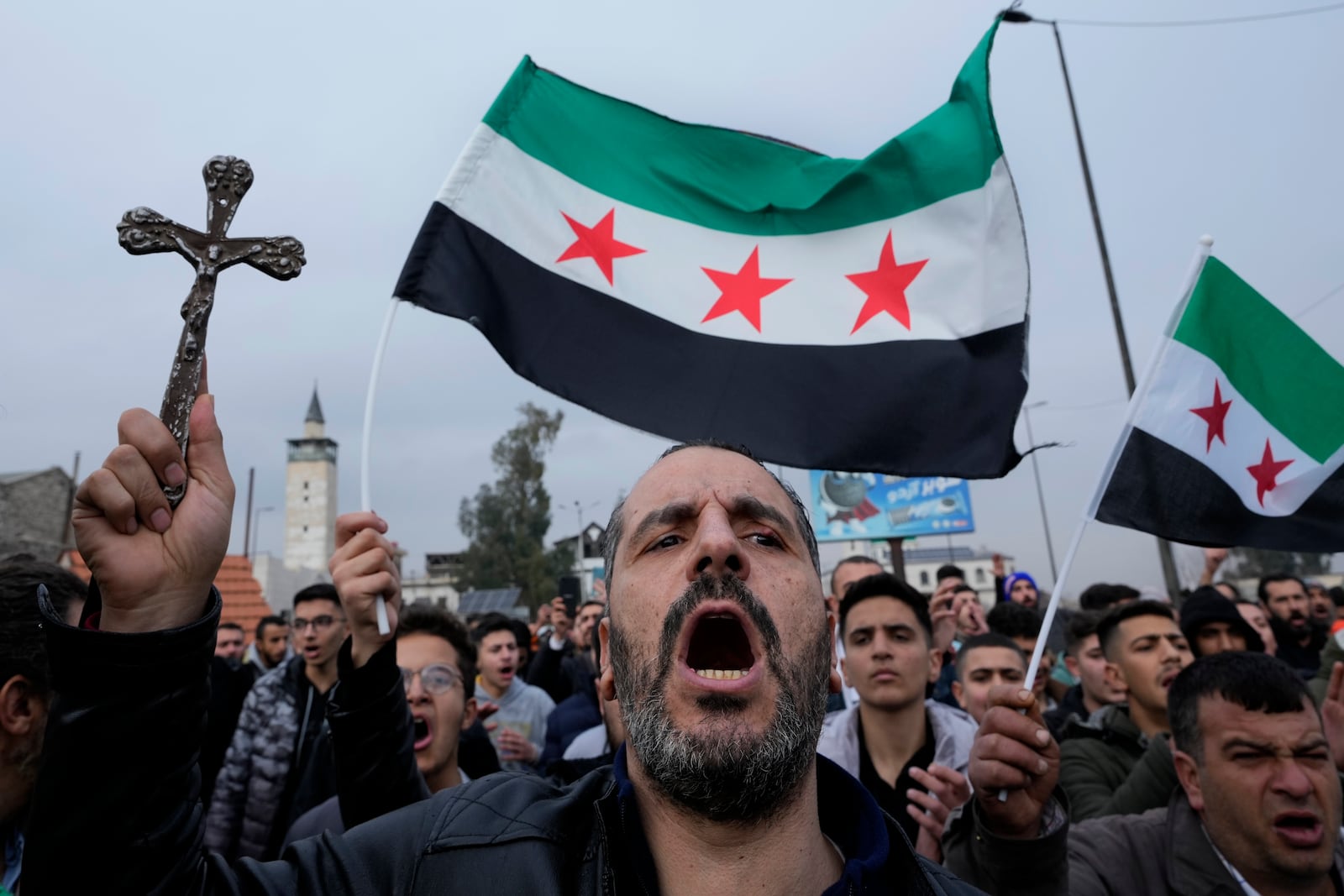 A Syrian Christian man holds up a cross and shouts slogans in Damascus, Syria, Tuesday, Dec. 24, 2024, during a protest march after a Christmas tree was set on fire in Hamah city on Sunday. (AP Photo/Hussein Malla)