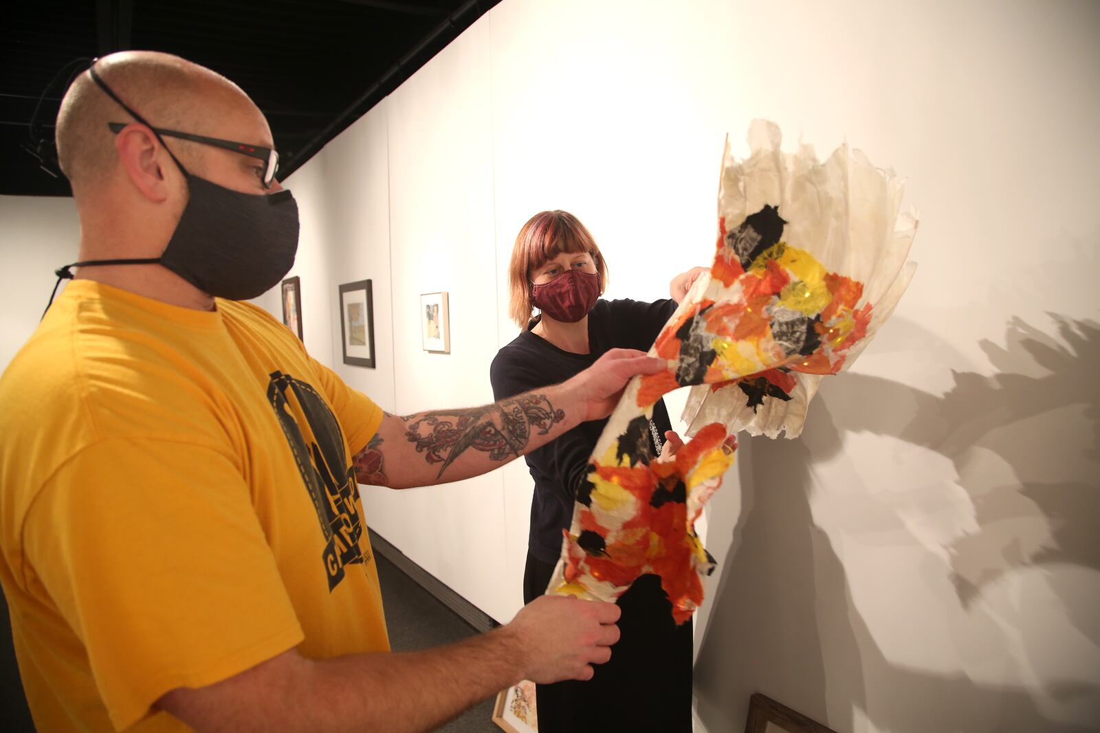 Adam Redding, program director at the Rosewood Centre and Shayna McConville, City of Kettering cultural arts manager, install the 31st Annual Dayton Works on Paper exhibition which opens Monday, Jan. 11 at Rosewood Gallery in Kettering’s Rosewood Arts Centre, 2655 Olson Dr. It will be on view through Feb. 19. LISA POWELL / STAFF