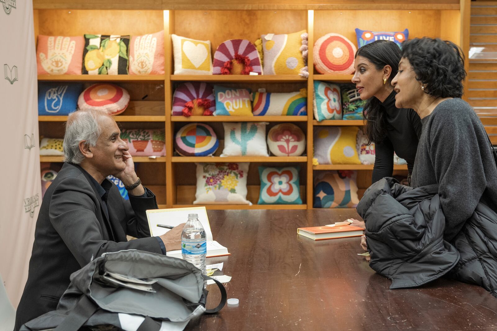 Pico Iyer, the bestselling author of "The Art of Stillness," signs books to Aparna Ramaswamy and Ranee Ramaswamy after presenting his book "Aflame: Learning from Silence" at Vroman's bookstore in Pasadena, Calif., on Tuesday, Jan. 28, 2025, in the wake of the devastating Eaton Fire that recently swept through parts of Pasadena and Altadena, forcing over 30,000 people to evacuate and burning thousands of structures. (AP Photo/Damian Dovarganes)