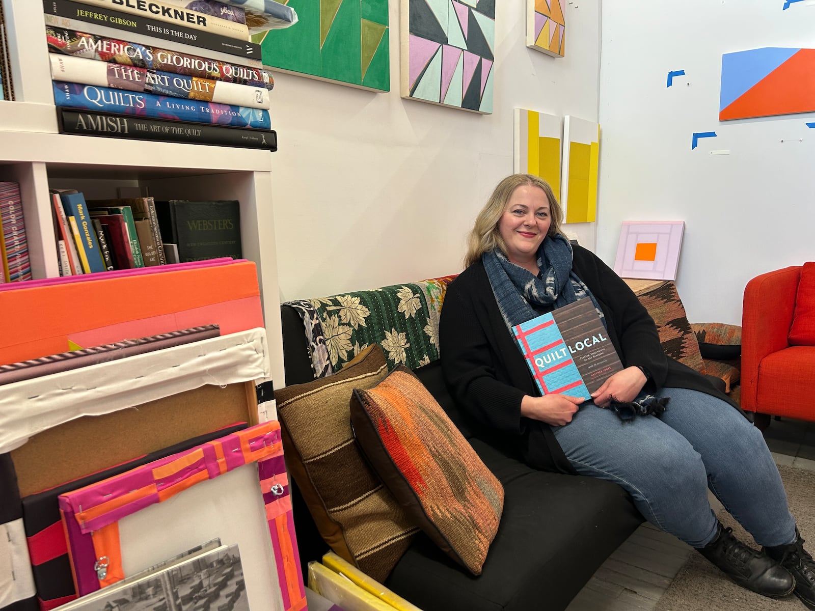 Artist Heather Jones in her Front Street studio holding her book entitled "Quilt Local: Finding Inspiration in the Everyday".