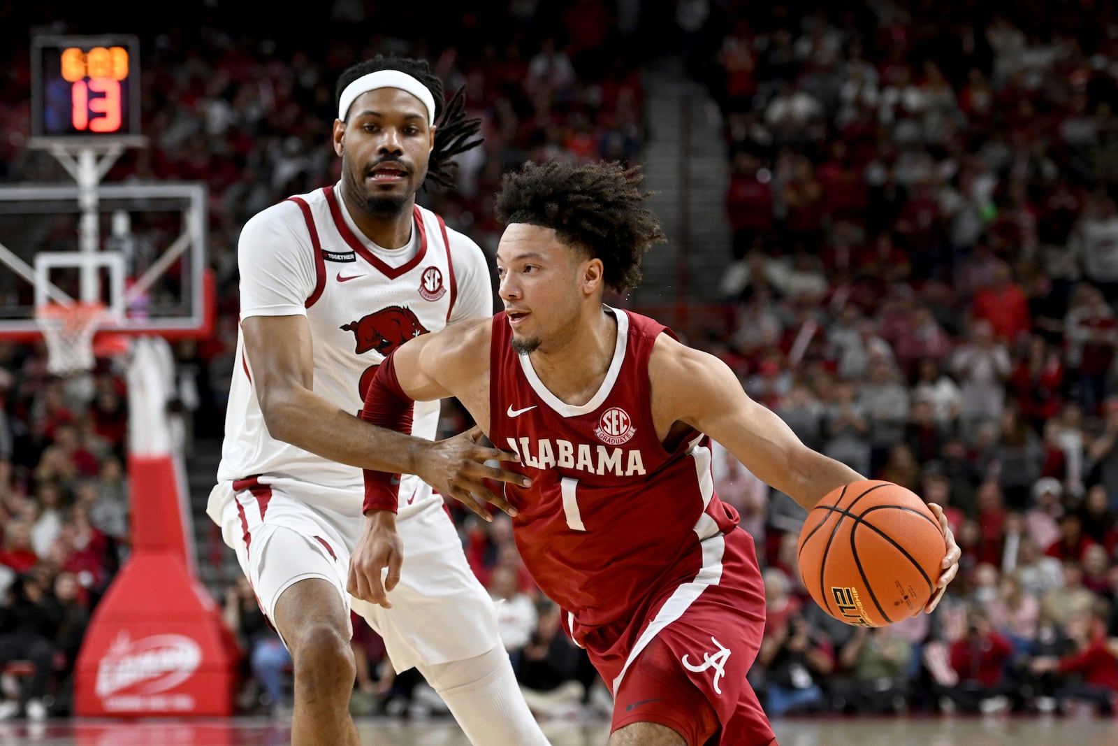 Alabama guard Mark Sears (1) drives past Arkansas forward Jonas Aidoo (9) during the first half of an NCAA college basketball game Saturday, Feb. 8, 2025, in Fayetteville, Ark. (AP Photo/Michael Woods)