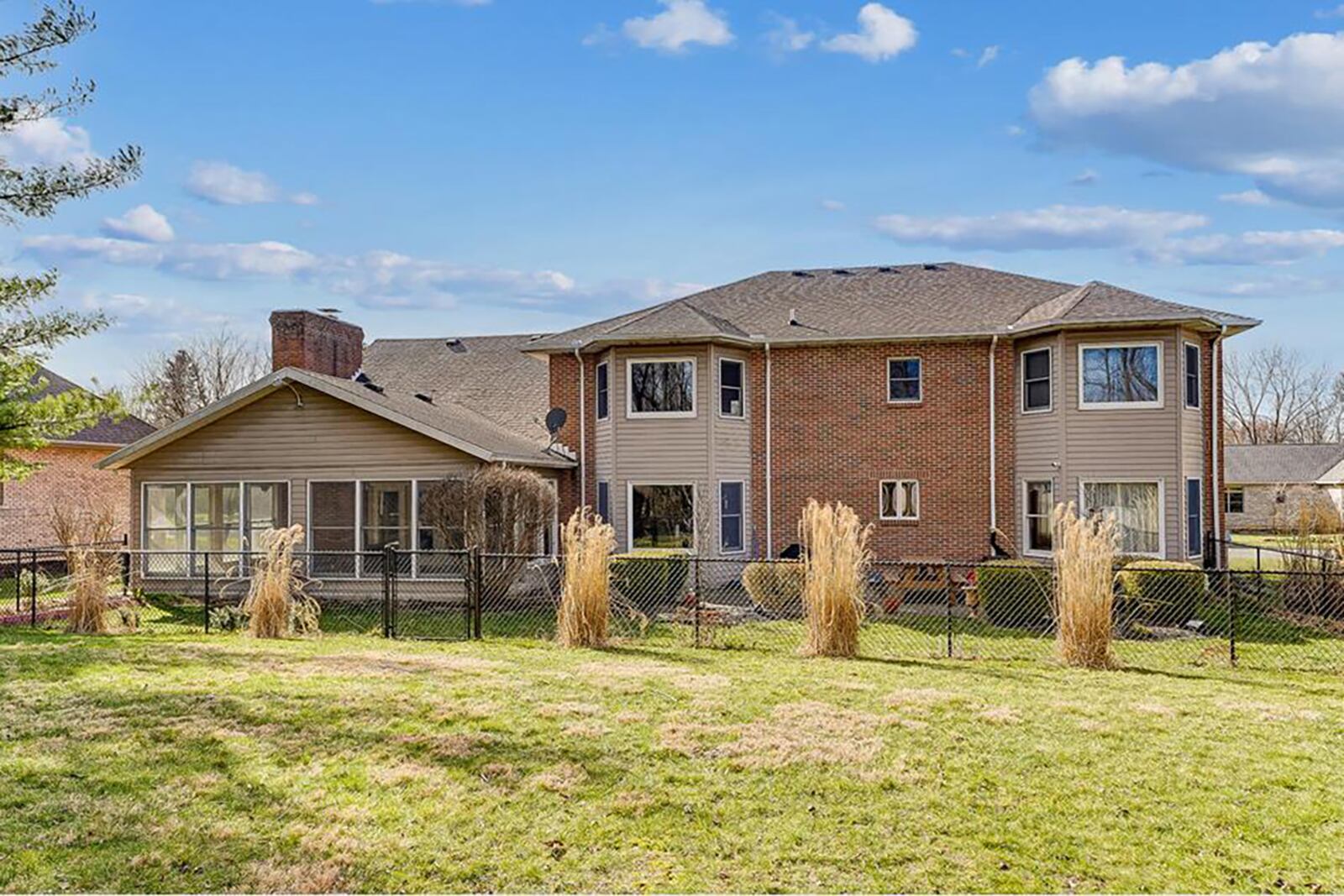 The rear of the home features a fence, sunroom, paver patio and two bay-window extensions on the first and second floors.