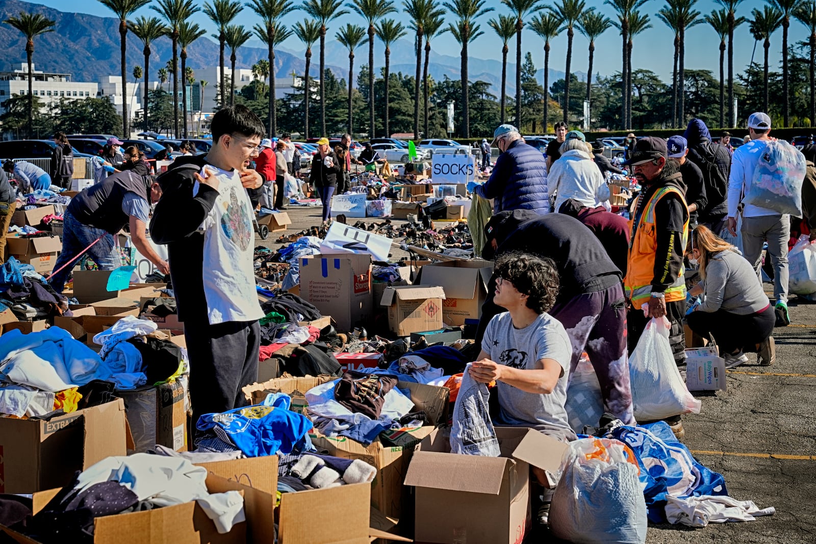 Ivan Benavidez, left and his brother Isaac who lost their home in the Altadena fire check on tee-shirts that might fit at a donation center at Santa Anita Park in Arcadia, Calif. on Wednesday, Jan. 15, 2025. (AP Photo/Richard Vogel)