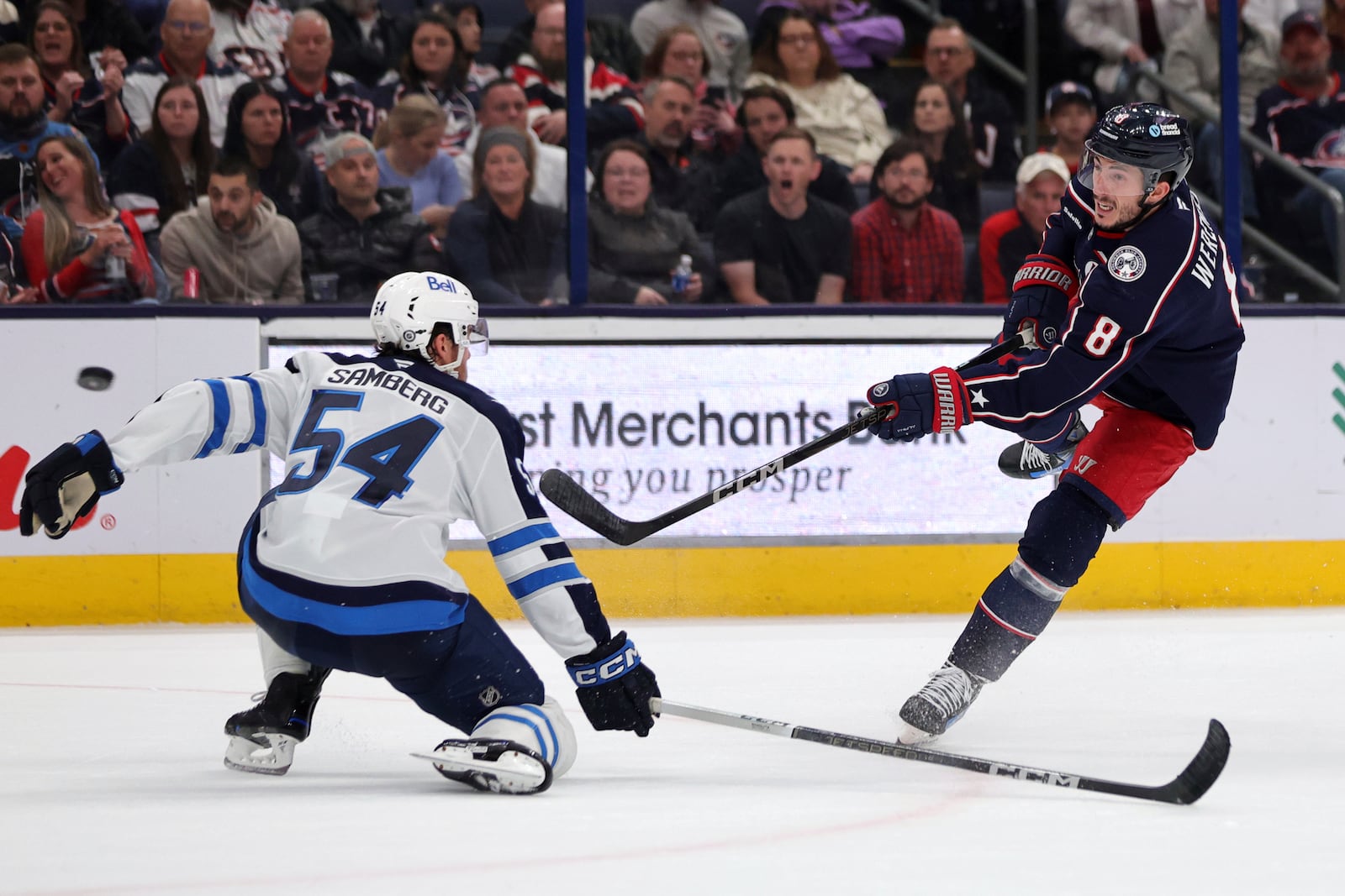 Columbus Blue Jackets defenseman Zach Werenski, right, shoots the puck in front of Winnipeg Jets defenseman Dylan Samberg during the second period of an NHL hockey game in Columbus, Ohio, Friday, Nov. 1, 2024. (AP Photo/Paul Vernon)