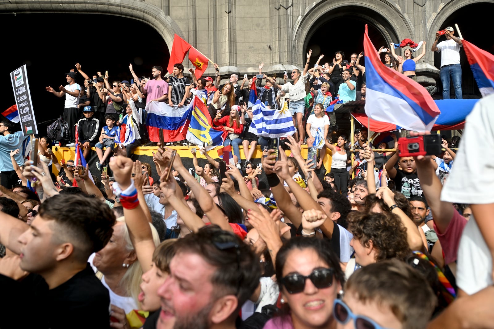 People greet Uruguay's newly sworn-in President Yamandu Orsi and Vice President Carolina Cosse as they ride past in an open car, on Inauguration Day in Montevideo, Uruguay, Saturday, March 1, 2025. (AP Photo/Santiago Mazzarovich)