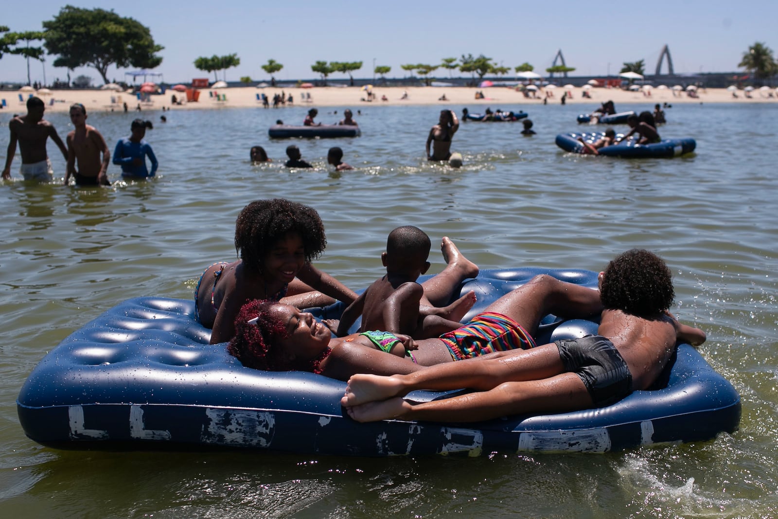 People lie on an inflatable mattress at the Piscinao de Ramos artificial beach during summer in Rio de Janeiro, Sunday, Feb. 16, 2025. (AP Photo/Bruna Prado)