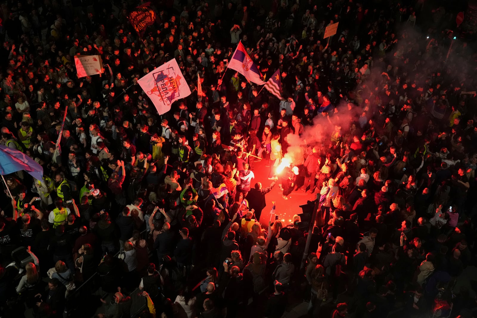 Protesters light flares as they gather ahead of a major rally this weekend in downtown Belgrade, Serbia, Friday, March 14, 2025. (AP Photo/Darko Vojinovic)