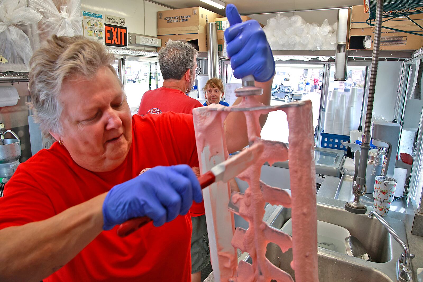 Rhonda Kramer cleans the strawberry ice cream off the mixer as she pulls it out of a 5 gallon can Wednesday, July 24, 2024. BILL LACKEY/STAFF