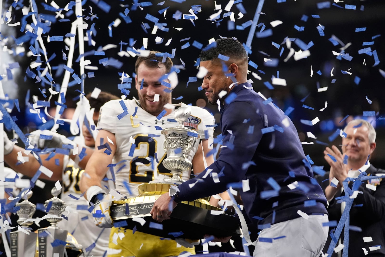 Notre Dame head coach Marcus Freeman and Notre Dame linebacker Jack Kiser (24) celebrate with the trophy after a quarterfinal game against Georgia in a College Football Playoff, Thursday, Jan. 2, 2025, in New Orleans. (AP Photo/Gerald Herbert)