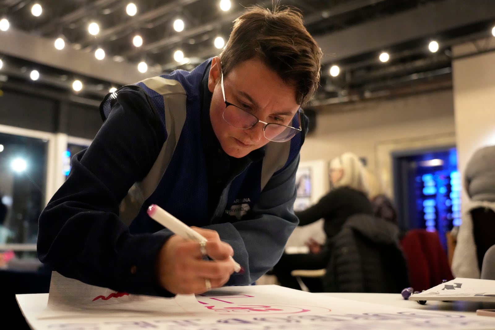 Cole Archer works on a protest sign during a meeting of NC Forward in High Point, N.C., Tuesday, Jan. 14, 2025. The group is traveling to Washington to take part in the People's March on Jan. 18 ahead of the inauguration. (AP Photo/Chuck Burton)