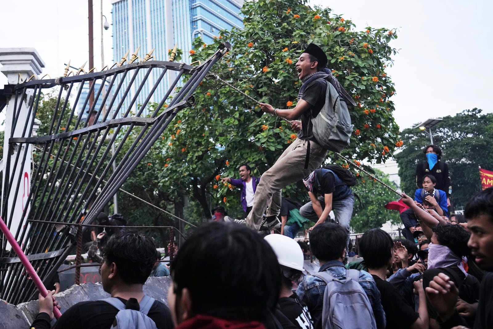 Protesters tear down the a part of the fence of the parliament building during a rally in Jakarta, Indonesia, Thursday, March 20, 2025, against the passing of a controversial revision of a military law that will allow military officers to serve in more government posts without resigning from the armed forces. (AP Photo/Tatan Syuflana)