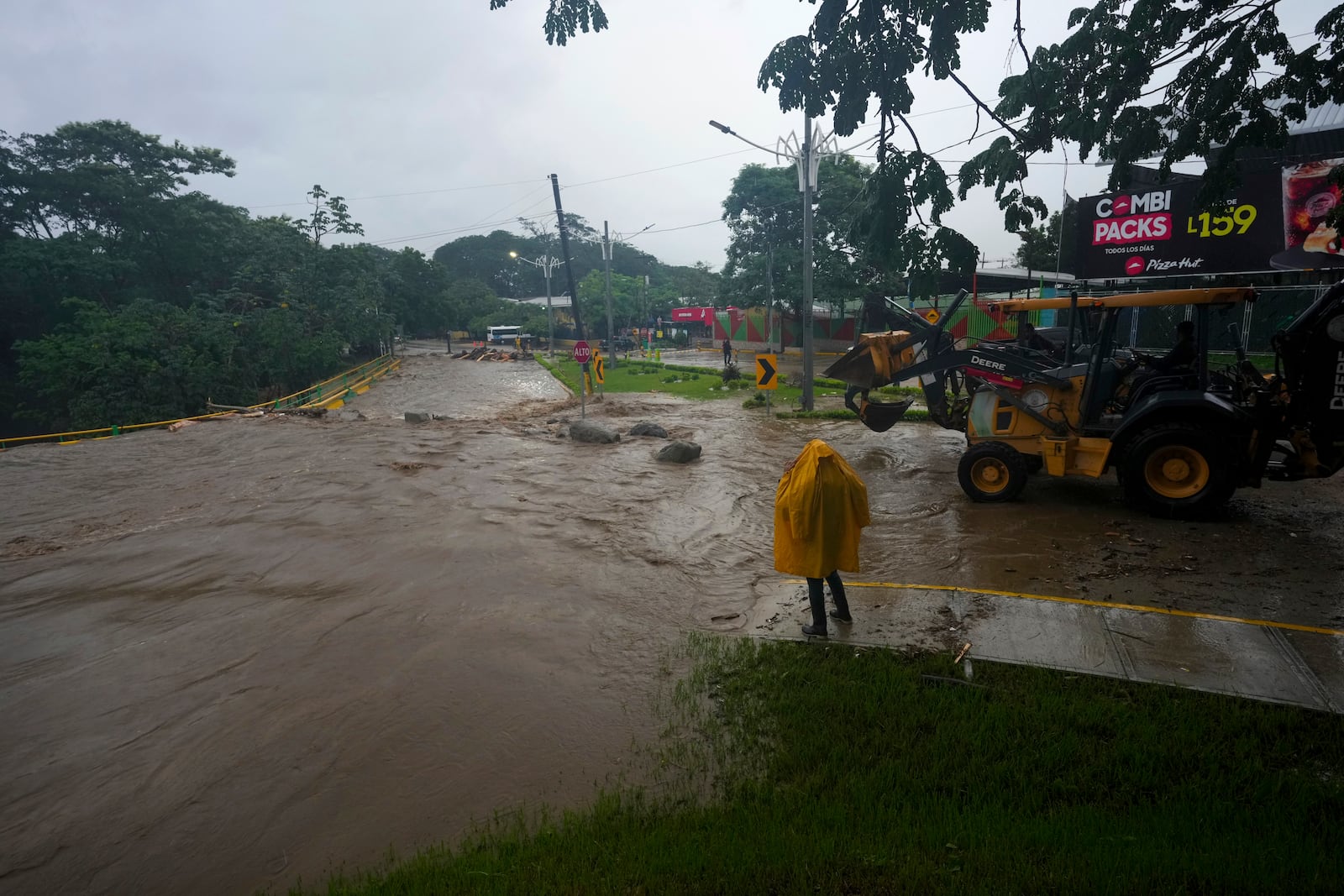 A worker stands alongside an overflowing river flooded by rains brought on by Tropical Storm Sara in San Pedro Sula, Honduras, Saturday, Nov. 16, 2024. (AP Photo/Moises Castillo)