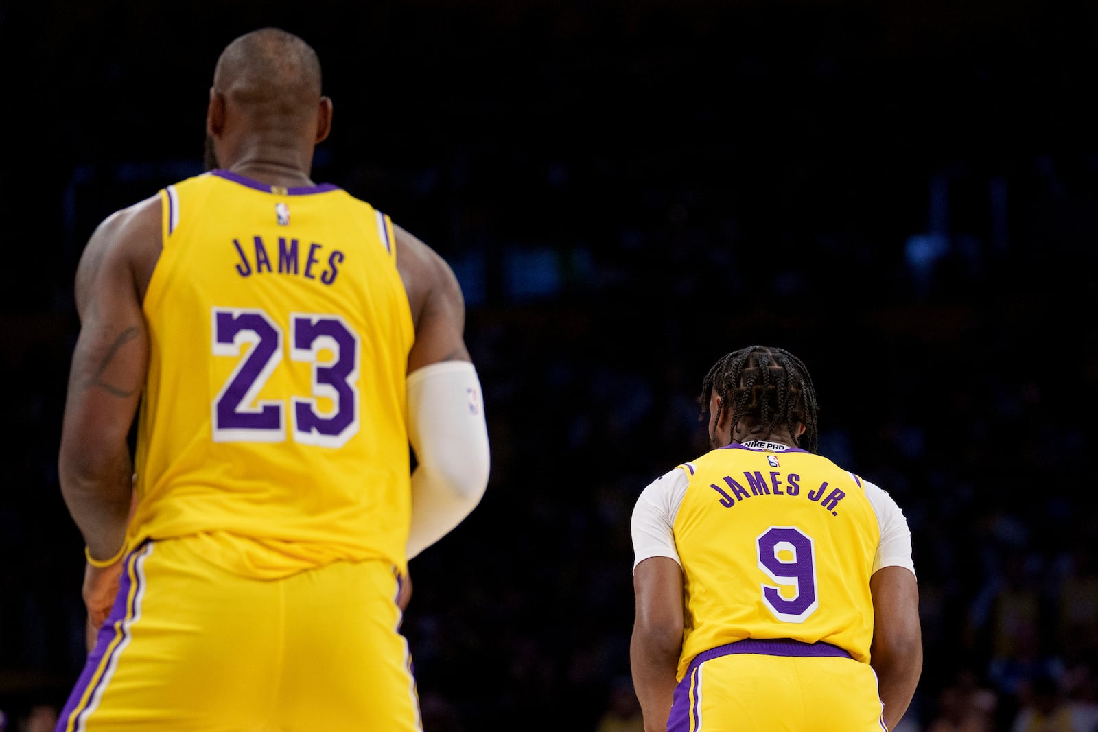 Los Angeles Lakers forward LeBron James (23) and guard Bronny James (9) stand on the court during the first half of an NBA basketball game against the Minnesota Timberwolves, Tuesday, Oct. 22, 2024, in Los Angeles. (AP Photo/Eric Thayer)