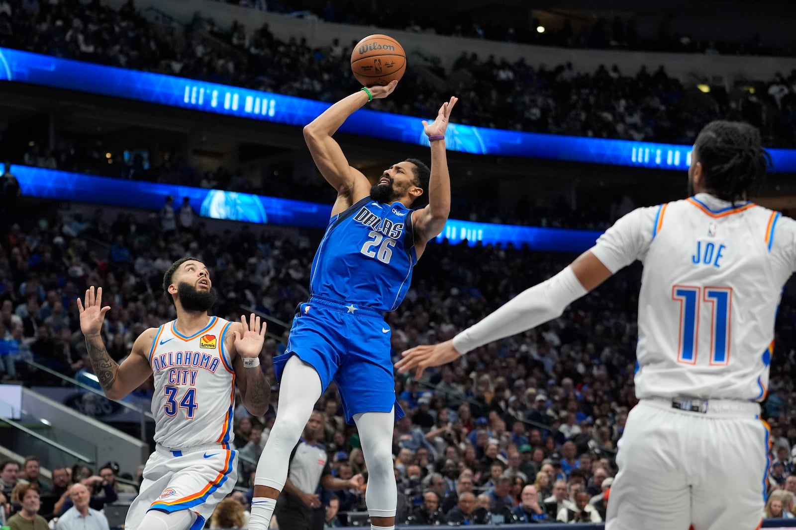 Dallas Mavericks guard Spencer Dinwiddie (26) scores against Oklahoma City Thunder forward Kenrich Williams (34) and guard Isaiah Joe (11) during the second half of an NBA basketball game Friday, Jan. 17, 2025, in Dallas. (AP Photo/LM Otero)