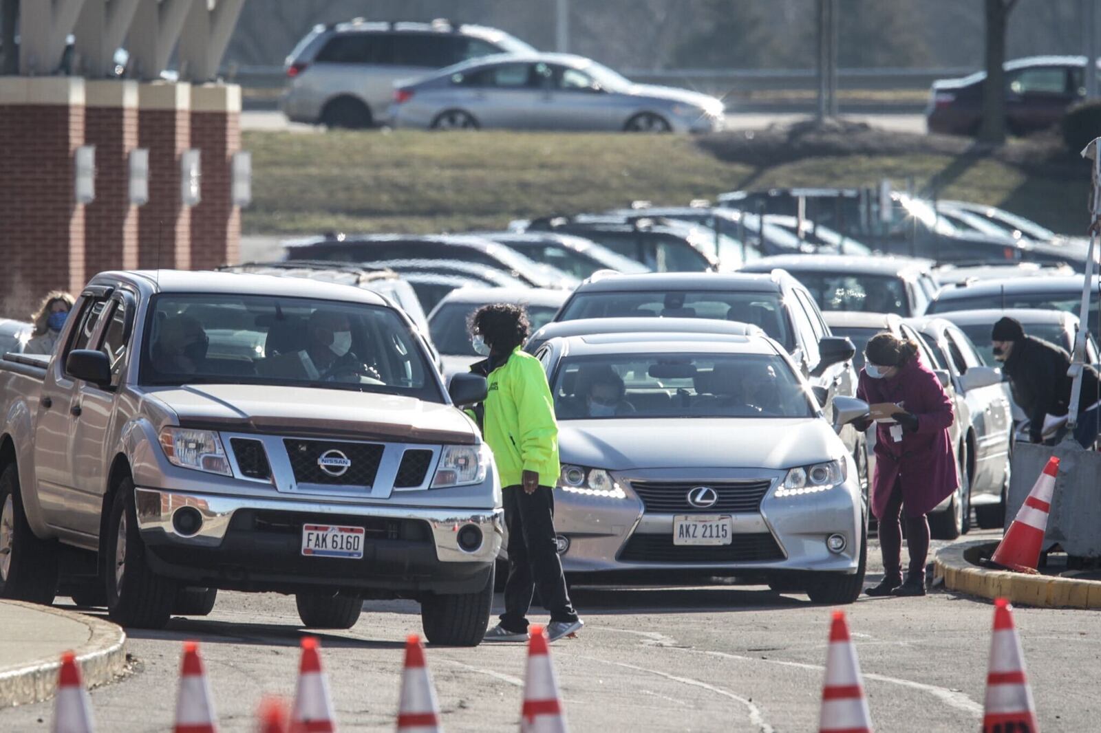 Vehicles were lined up in the street outside University of Dayton Arena Thursday morning for a drive-thru coronavirus vaccine clinic. JIM NOELKER/STAFF