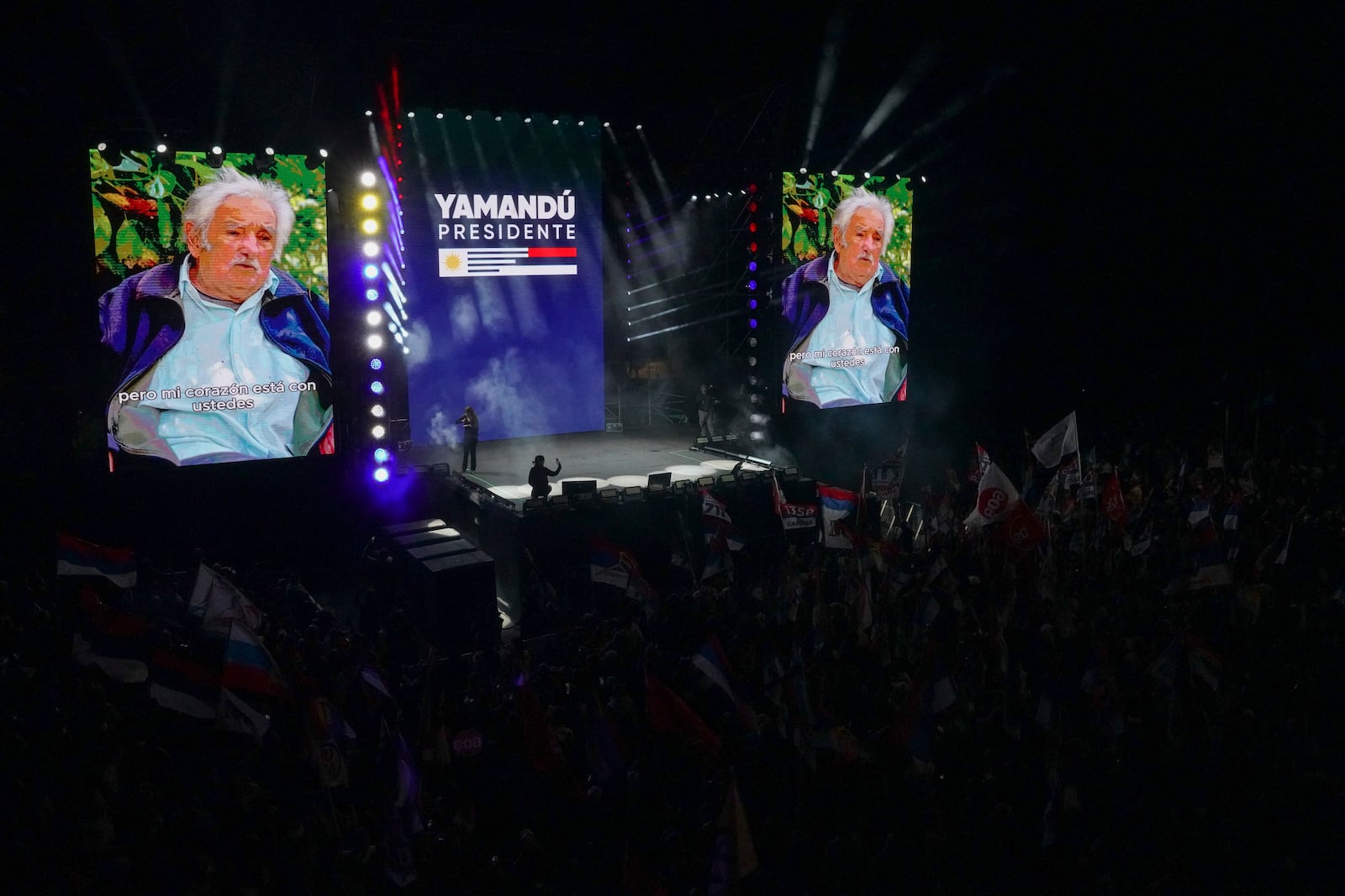 A screen shows former President Jose Mujica delivering a message during a rally for Frente Amplio presidential candidate Yamandu Orsi five days ahead of elections in Montevideo, Uruguay, Tuesday, Oct. 22, 2024. (AP Photo/Matilde Campodonico)