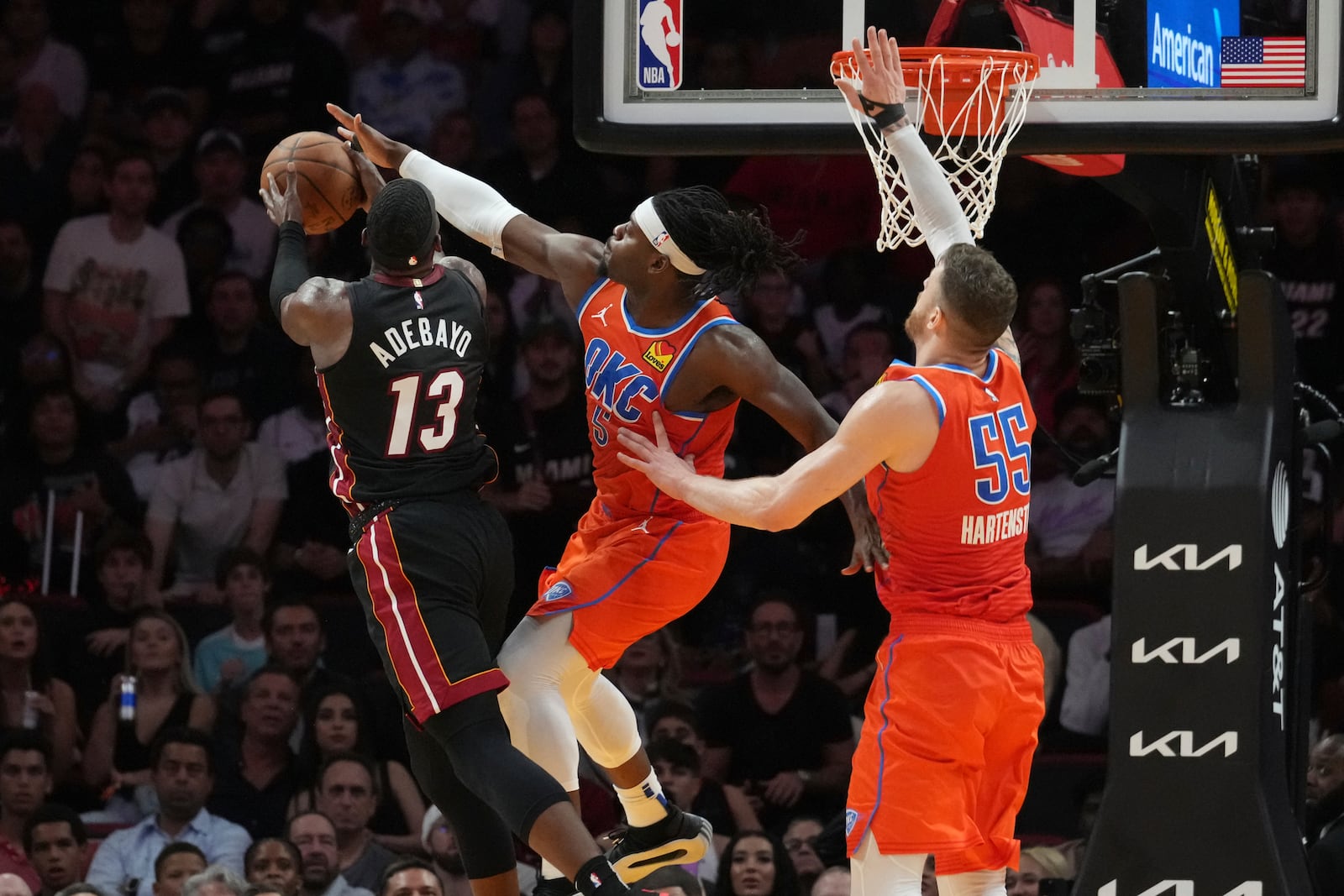 Oklahoma City Thunder guard Luguentz Dort (5) blocks a drive to the basket by Miami Heat center Bam Adebayo (13) during the first half of an NBA basketball game, Friday, Dec. 20, 2024, in Miami. (AP Photo/Marta Lavandier)