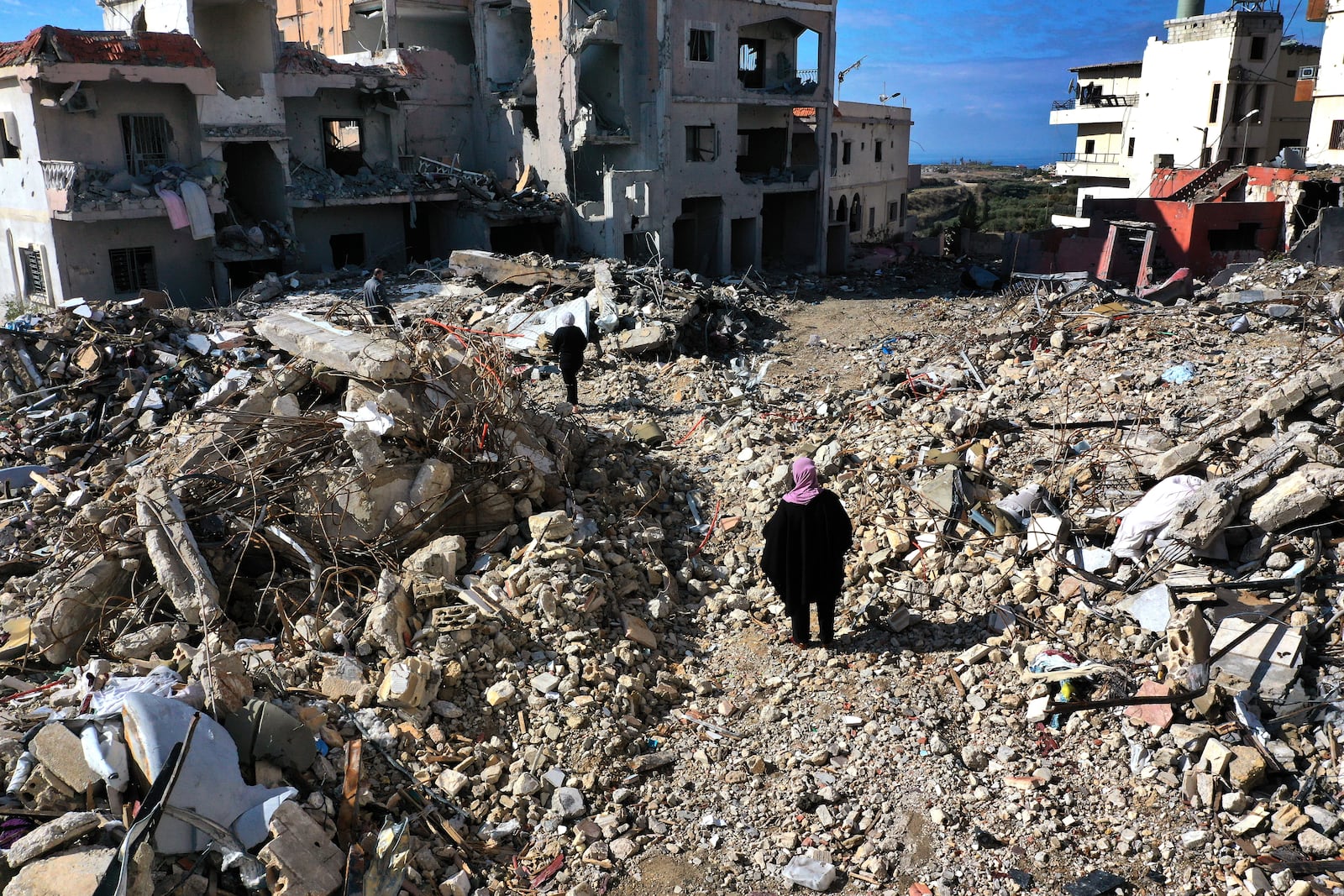 Residents walk past destroyed buildings as they return to Qana village, southern Lebanon, Thursday, Nov. 28, 2024 following a ceasefire between Israel and Hezbollah that went into effect on Wednesday.(AP Photo/Hussein Malla)