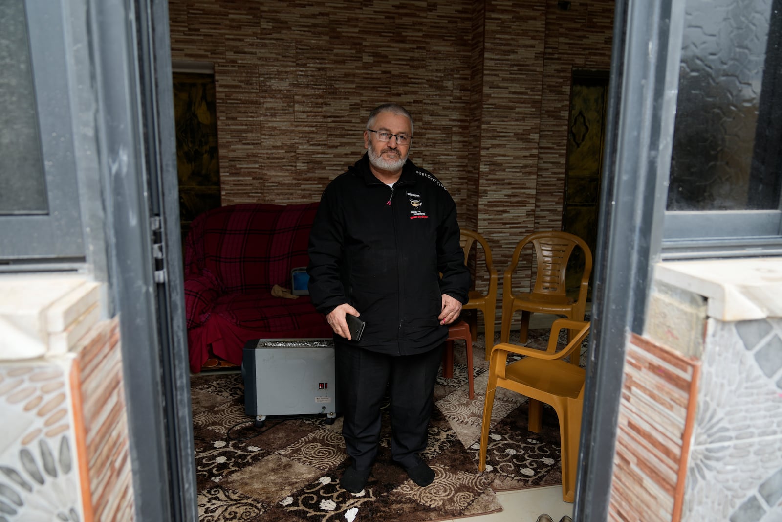 Mohammed Shula poses for a photo inside a relative's house where he and his wife have taken refuge at the West Bank village of Kafr al-Labad, Monday, Feb. 10, 2025. (AP Photo/Nasser Nasser)