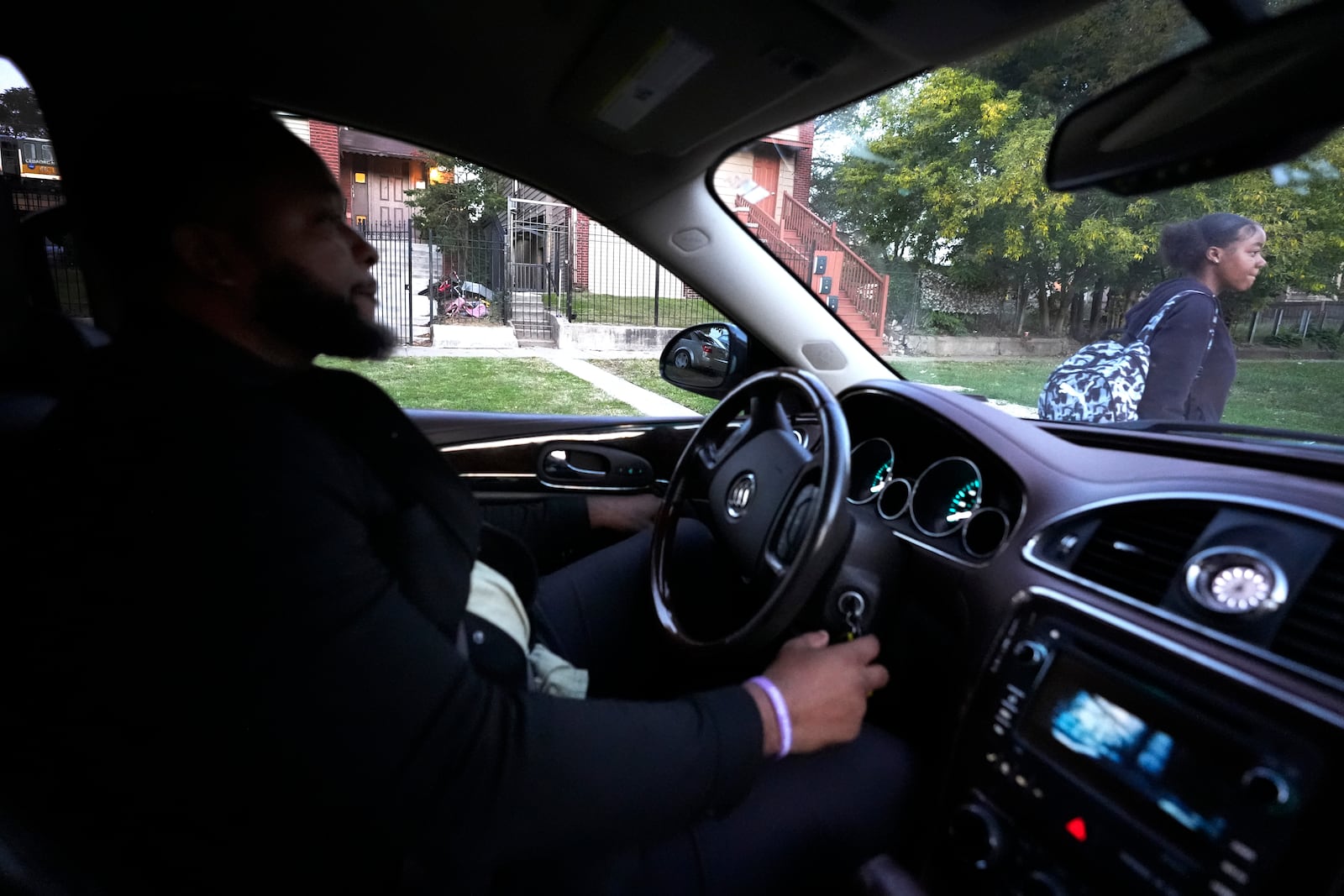 Takia Phillips, 15, right, walks around the car of PiggyBack Network co-founder & CEO Ismael El-Amin, on Friday, Oct. 18, 2024, as Phillips and another child are driven to school as part of the ride-share network in Chicago. (AP Photo/Charles Rex Arbogast)