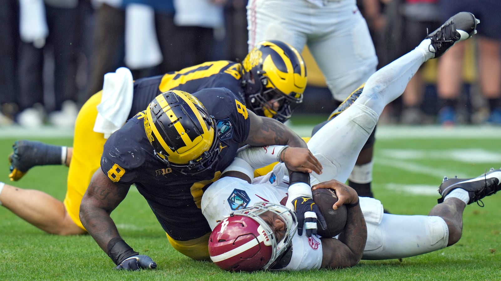 Michigan defensive end Derrick Moore (8) sacks Alabama quarterback Jalen Milroe (4) during the first half of the ReliaQuest Bowl NCAA college football game Tuesday, Dec. 31, 2024, in Tampa, Fla. (AP Photo/Chris O'Meara)