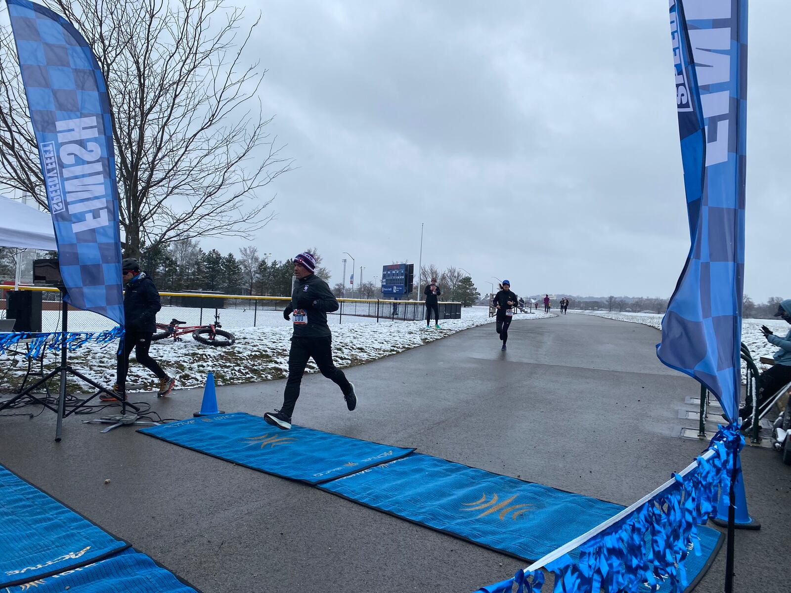 A runner crosses the finish line at the Hoopla Four Miler near University of Dayton Arena on March 12, 2023. Eileen McClory / Staff