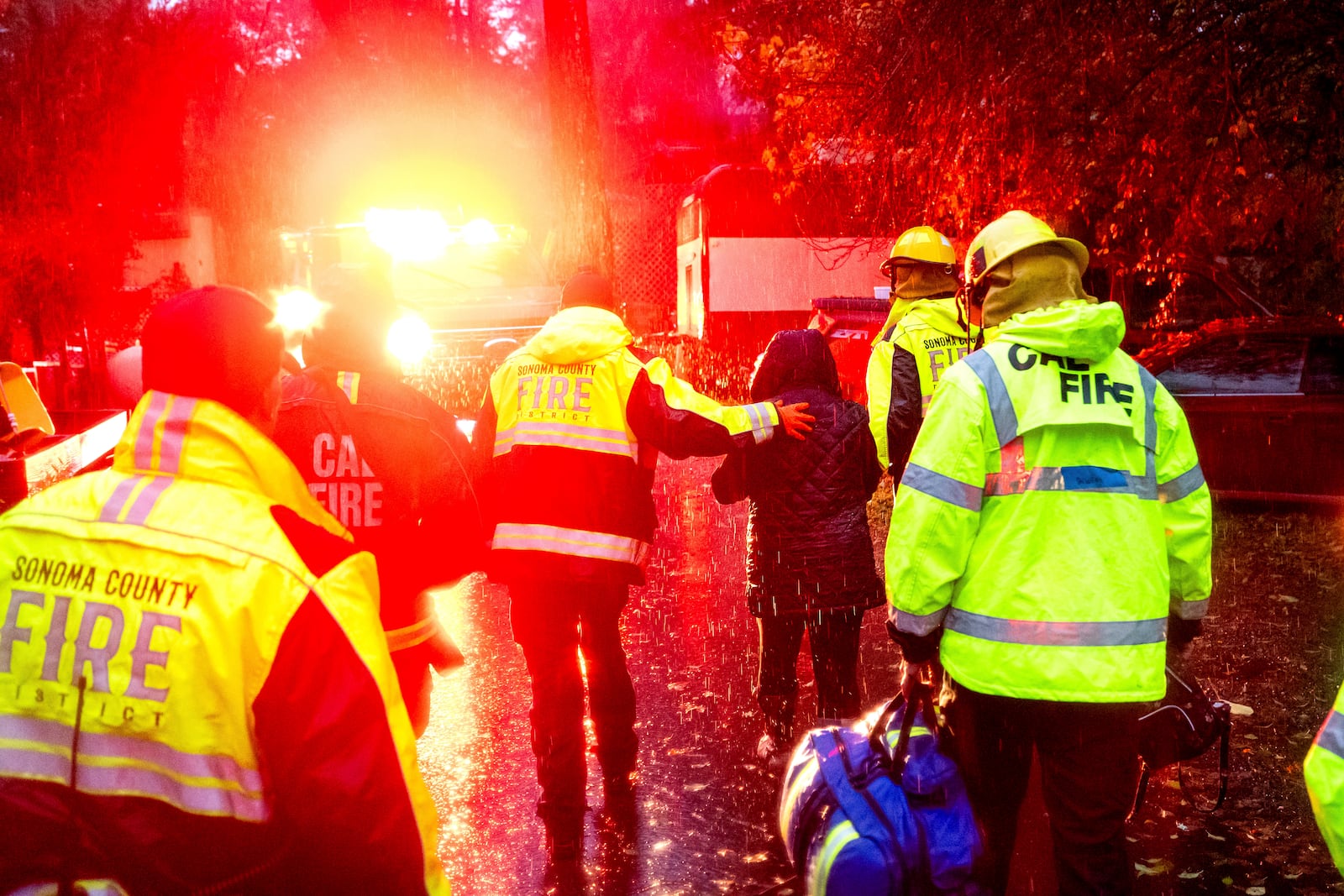 Firefighters help a woman from a home after a tree toppled onto it during heavy rains on Wednesday, Nov. 20, 2024, in the Forest Hills community of unincorporated Sonoma County, Calif. (AP Photo/Noah Berger)