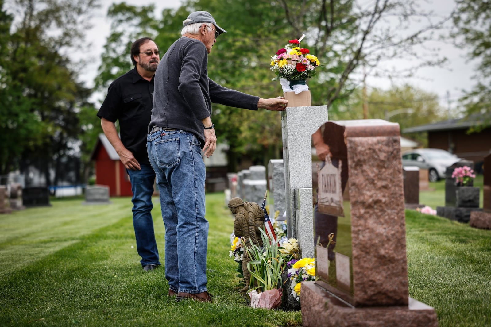 Jim Skaggs places flowers on the grave of Sgt. Gary McKiddy at Highland Memorial Cemetery in Miamisburg. Both men served together in Vietnam. McKiddy rescued Skaggs from a burning helicopter and died when the helicopter exploded. The man on the left is McKiddy brother Rick McKiddy on the left. JIM NOELKER/STAFF