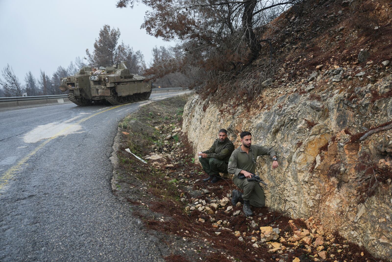 Israeli soldiers take cover on the side of the road during an alert of incoming rockets, near Kiryat Shmona, northern Israel Sunday Nov. 24, 2024. (AP Photo/Ohad Zwigenberg)