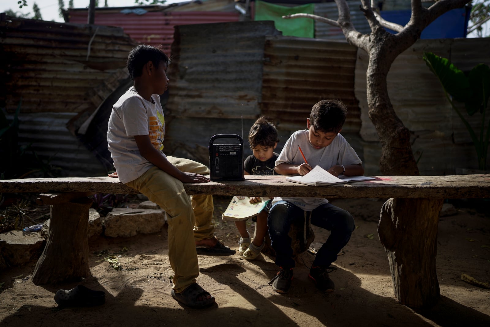 Indigenous children do their homework outside their home in the Villa del Sol neighborhood on the outskirts of Riohacha, Colombia, Tuesday, Feb. 4, 2025. (AP Photo/Ivan Valencia)