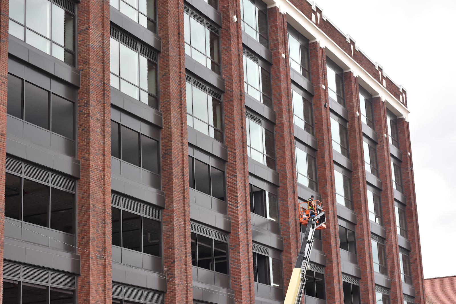 Construction crews work on the exterior of the Delco building, a massive mixed-use development located just south of the Day Air Ballpark, where the Dayton Dragons play baseball in downtown Dayton. CORNELIUS FROLIK / STAFF