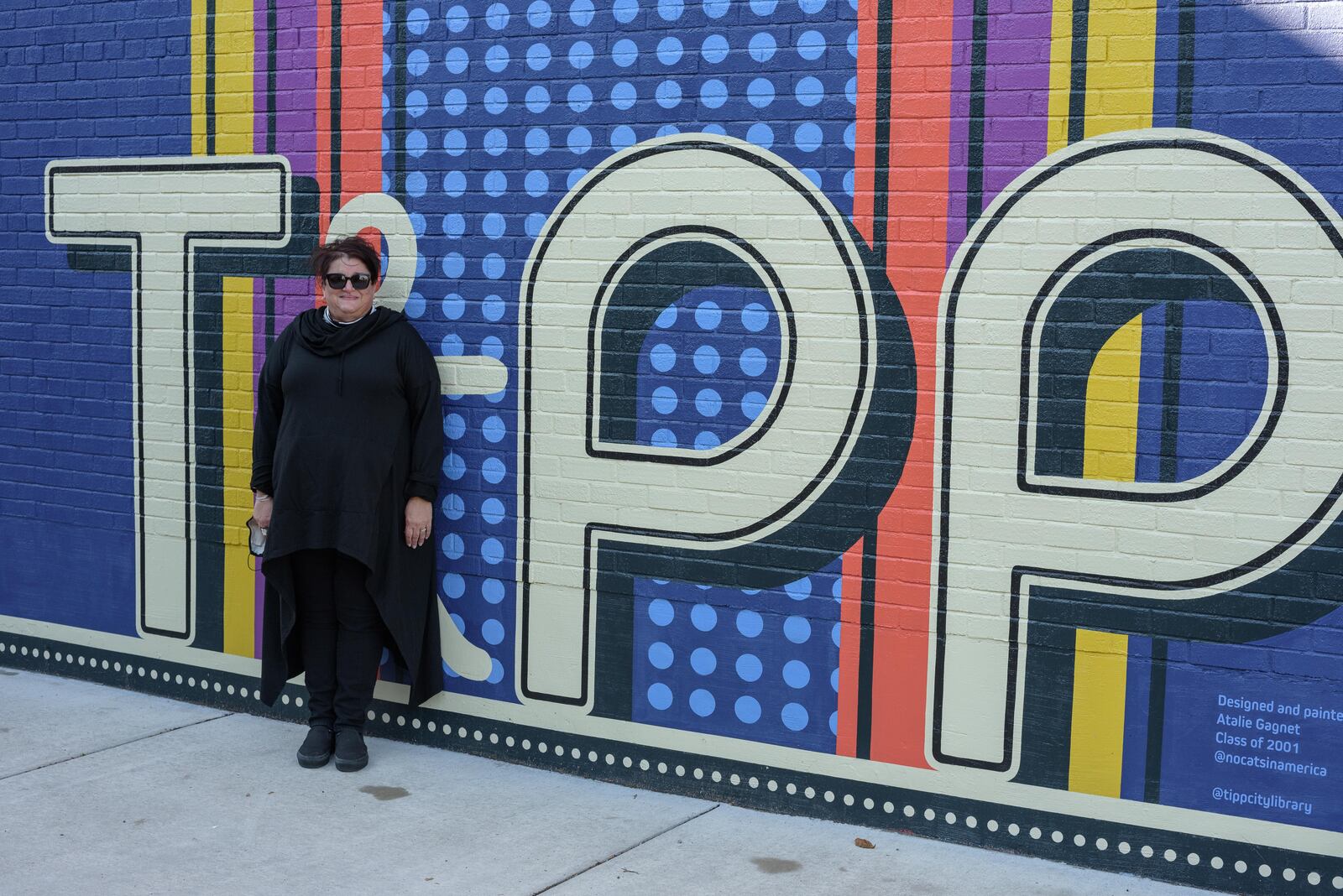 Lisa Santucci, Director of the Tipp City Public Library demonstrates how to take a photo at the new "See Yourself in Tipp" mural on October 31, 2020. TOM GILLIAM