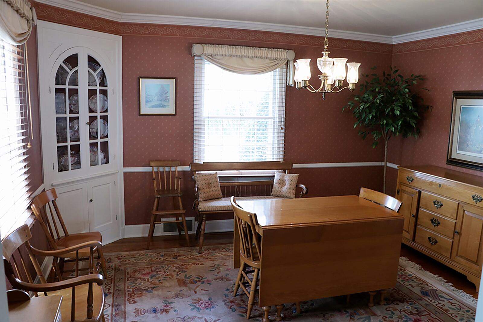 The formal dining room has a built-in corner china hutch. The built-in hutch with arched glass-panel doors shows display shelves while cabinet doors provide extra storage. Crown molding, chair rail and bold floor molding accent the dining room with hardwood flooring. CONTRIBUTED PHOTO BY KATHY TYLER