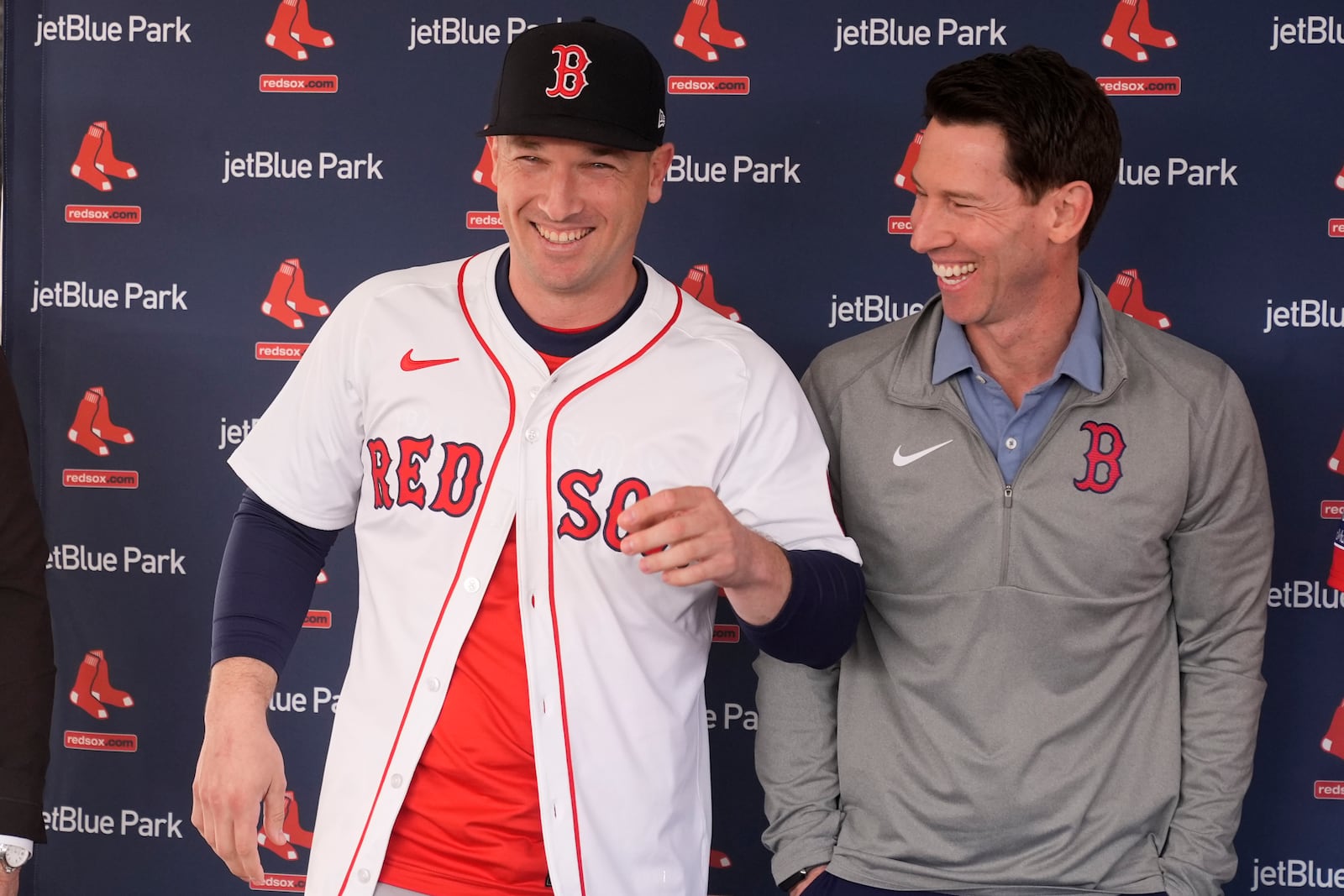 Craig Breslow, chief baseball officer for the Boston Red Sox, laughs after putting a jersey on Alex Bregman as he is introduced after signing a three year contract with the Red Sox in Fort Myers, Fla., Sunday, Feb. 16, 2025. (AP Photo/Gerald Herbert)