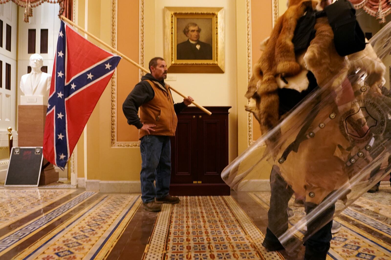 A member of the mob of Trump supporters carries the Confederate flag inside the Capitol building as Congress met to President-elect Joe Biden's victory, on Wednesday, Jan. 6, 2021. Experts say the actions of President Donald Trump and his loyalists are harder to stop than a coup — citing anti-democratic slides in Turkey and Venezuela as closer examples. (Erin Schaff/The New York Times)