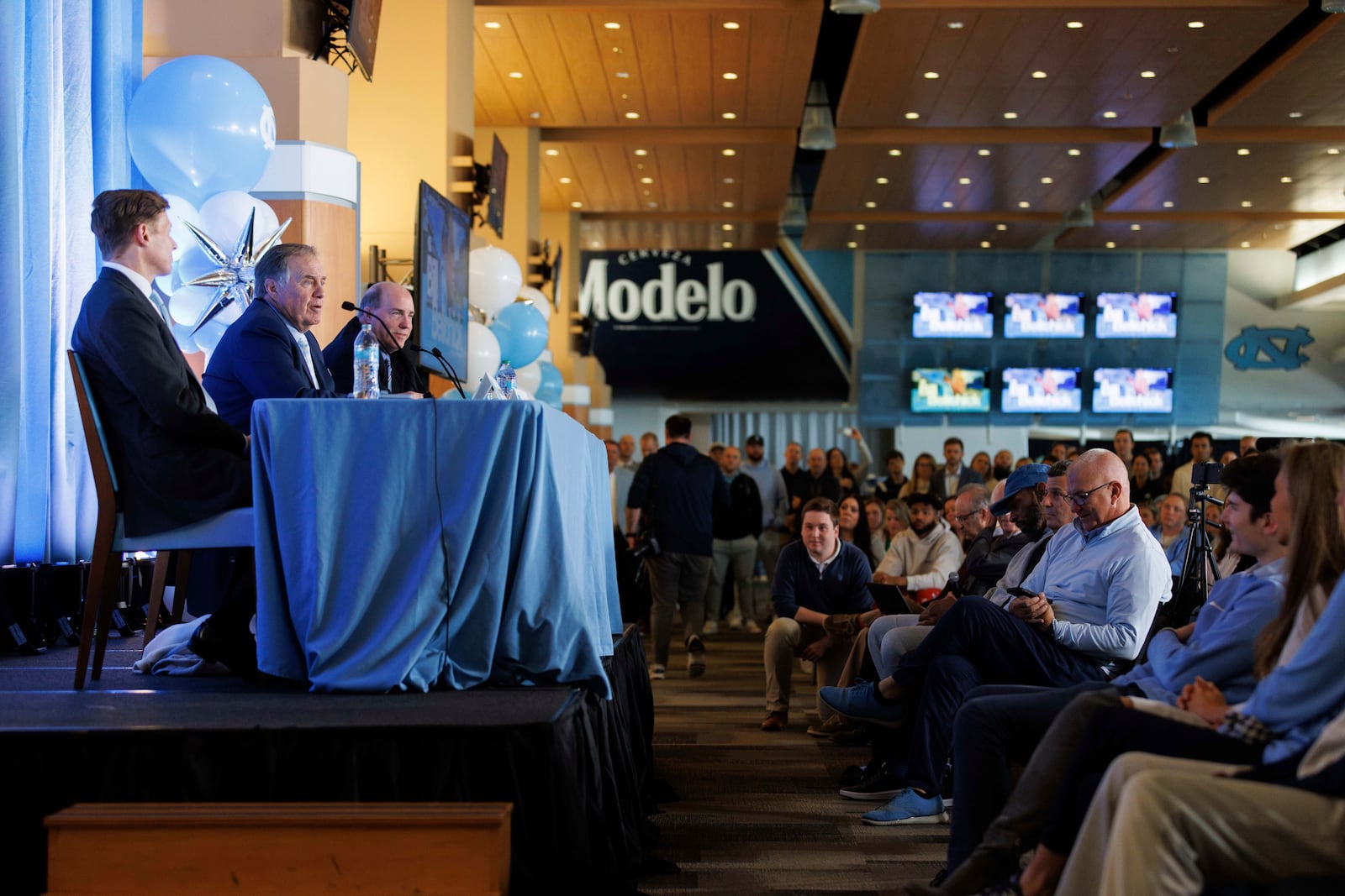 Members of the media and the public listen as new North Carolina football coach Bill Belichick, second from left, speaks at an NCAA college football press conference in Chapel Hill, N.C., Thursday, Dec. 12, 2024. (AP Photo/Ben McKeown)