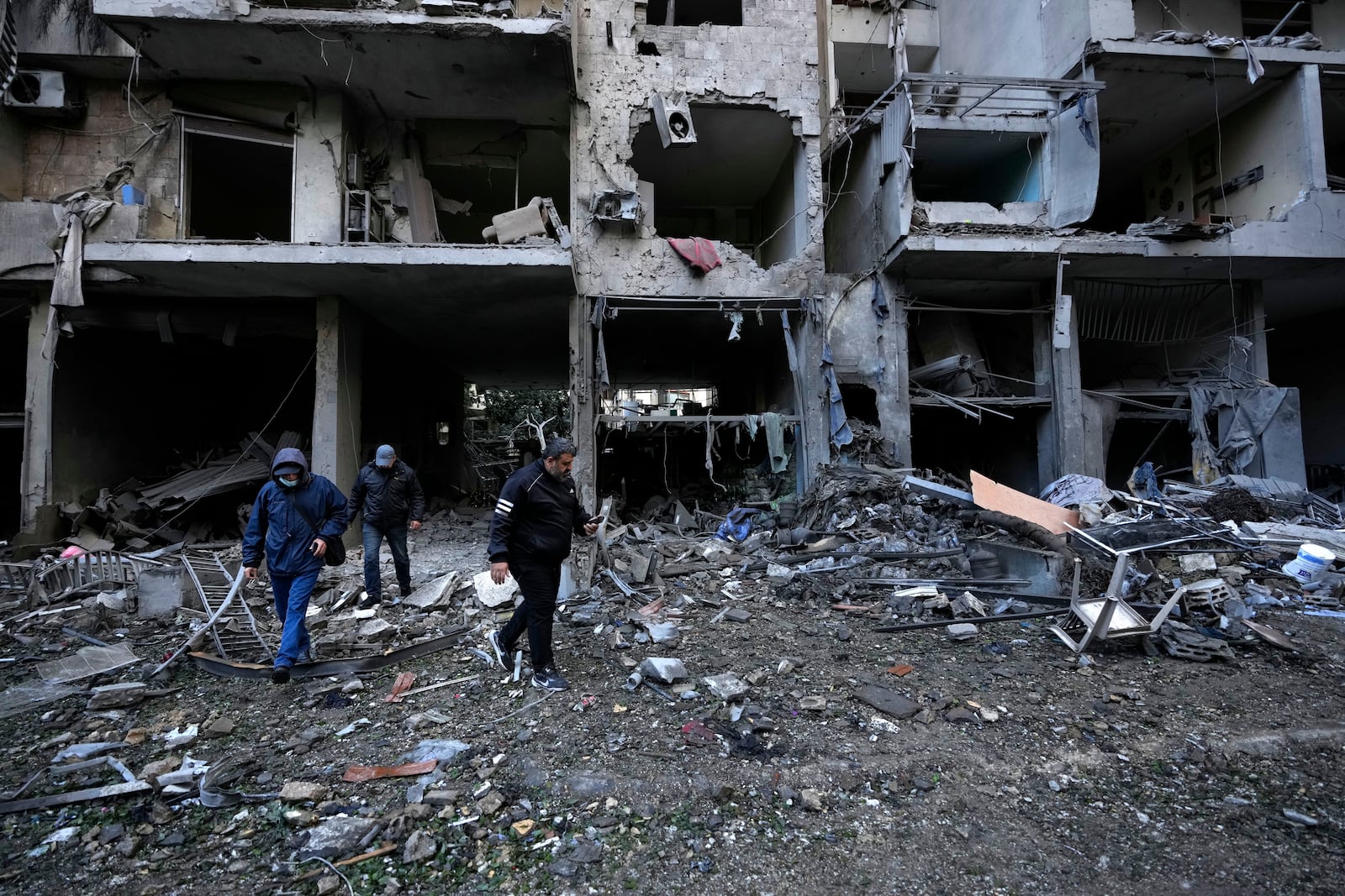 Residents pass in front of destroyed building which was resulted from Sunday's Israeli airstrike in Dahiyeh, in the southern suburb of Beirut, Lebanon, Monday, Nov. 25, 2024. (AP Photo/Hussein Malla)