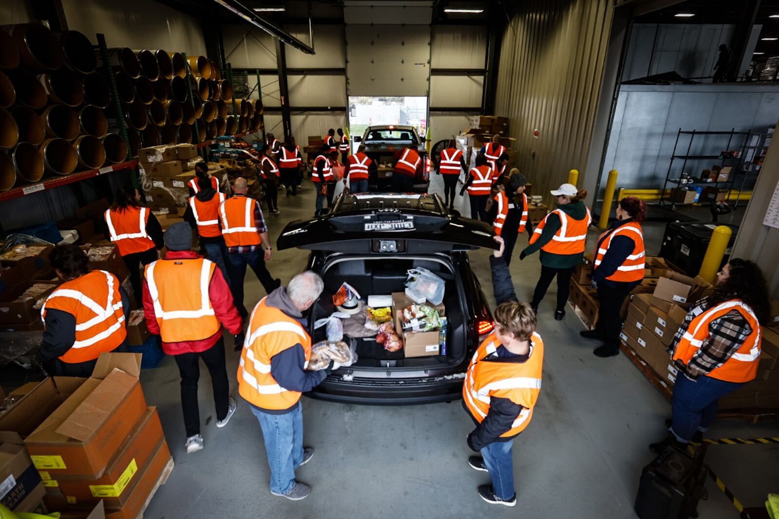 Around 25 volunteers help load vehicles with food Thursday morning November 17, 2022 at the Dayton Foodbank. JIM NOELKER/STAFF