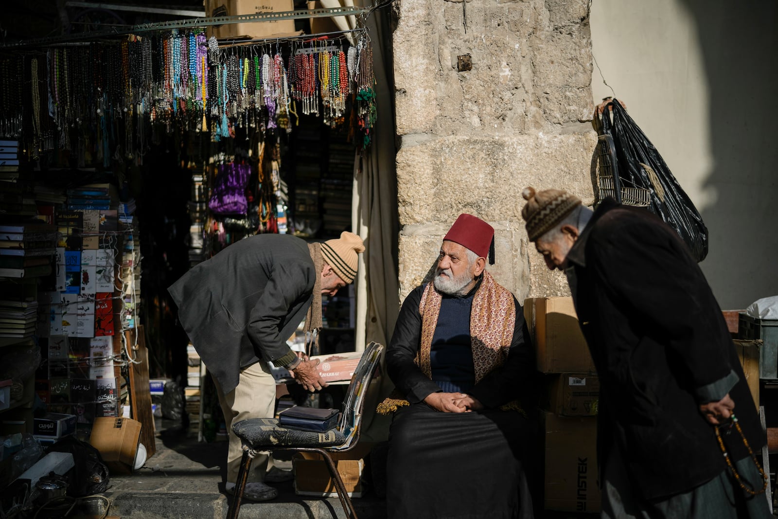 A man sits next to a vendor setting up his shop in the Old City , near the Umayyad Mosque, ahead of Friday prayers in Damascus, Syria, Friday, Dec. 20, 2024. (AP Photo/Leo Correa)