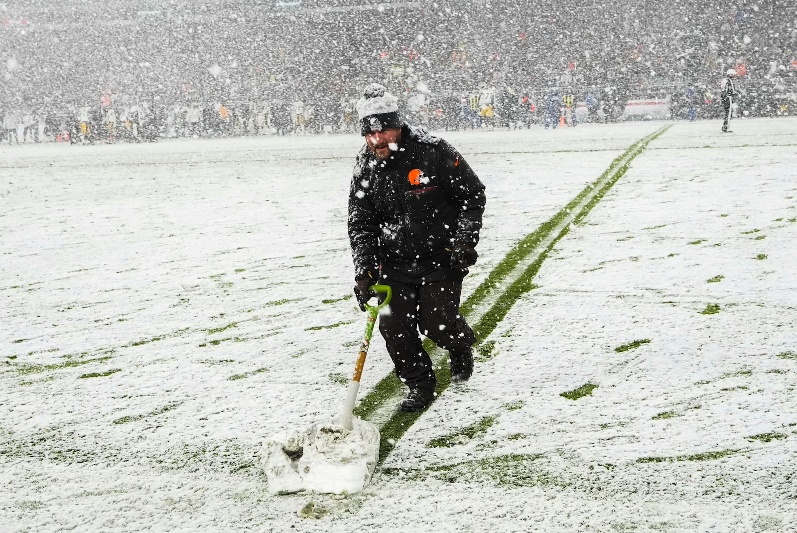 A groundskeeper shovels snow on the field in the second half of an NFL football game between the Cleveland Browns and the Pittsburgh Steelers, Thursday, Nov. 21, 2024, in Cleveland. (AP Photo/Sue Ogrocki)