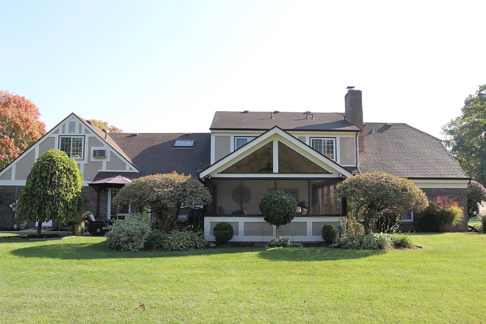 In the back, a concrete patio is nestled among the landscaping and is next to a screen-enclosed porch.