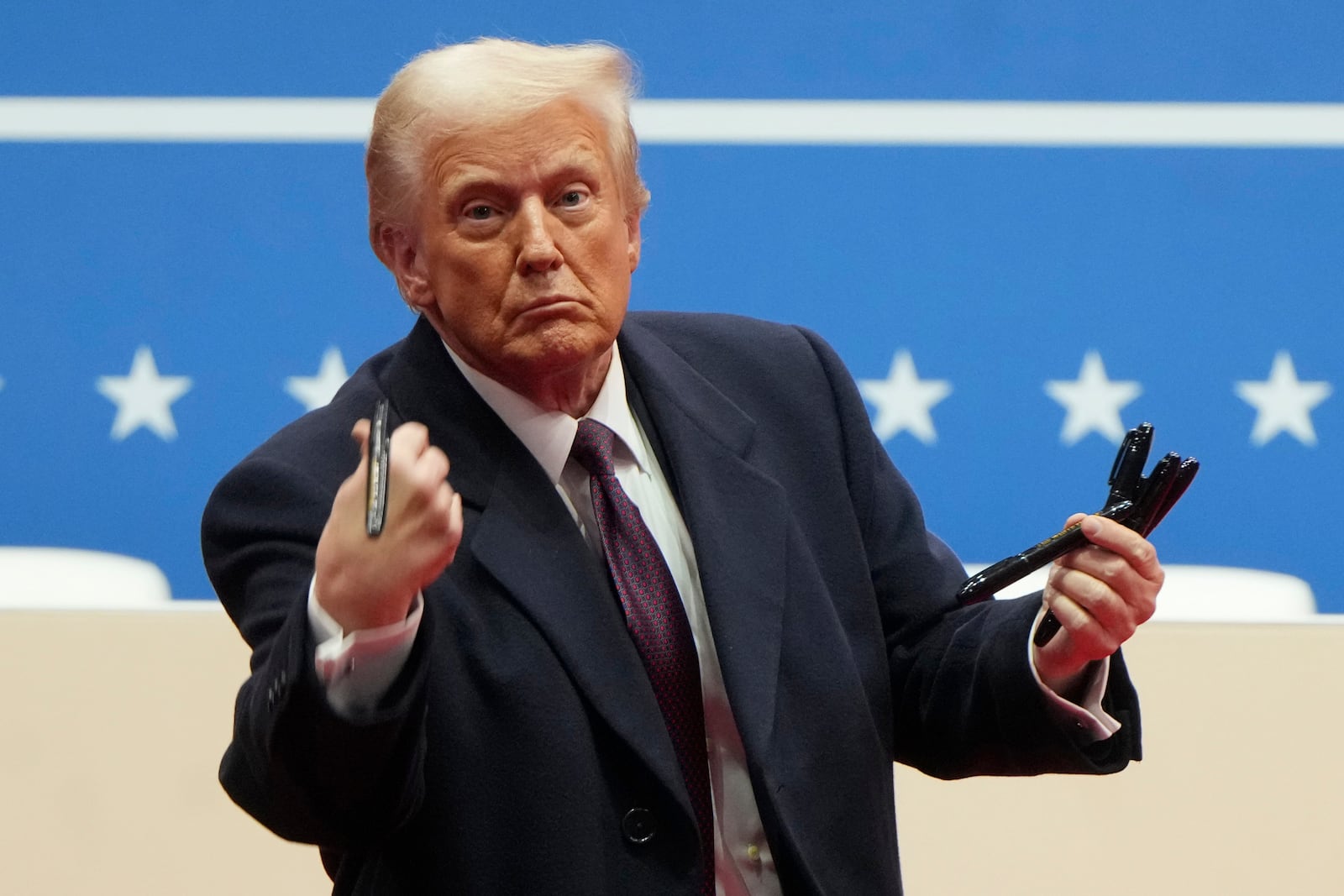 President Donald Trump throws pens used to sign executive orders to the crowd during an indoor Presidential Inauguration parade event in Washington, Monday, Jan. 20, 2025. (AP Photo/Matt Rourke)