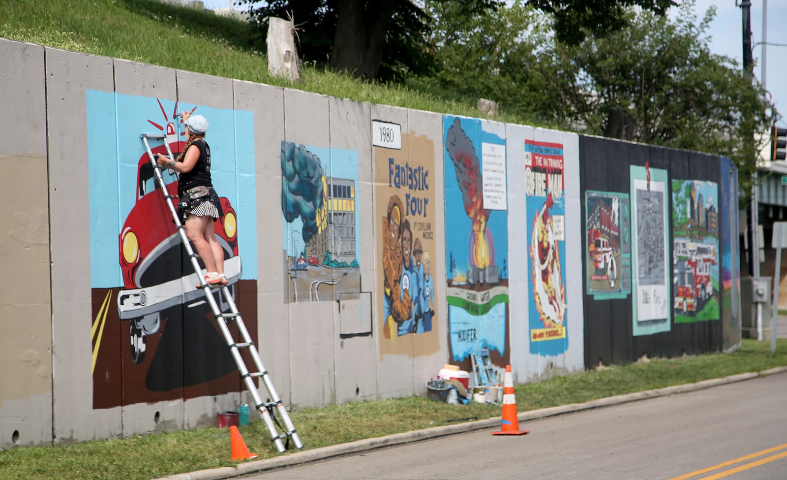 Dayton Fire Fighters Local 136 has teamed up with mural artist Tiffany Clark to create a 20-panel mural along Buckeye Street between Main and Warren Streets. The mural will tell the history of the Dayton Fire Department in vintage comic book style.  LISA POWELL / STAFF