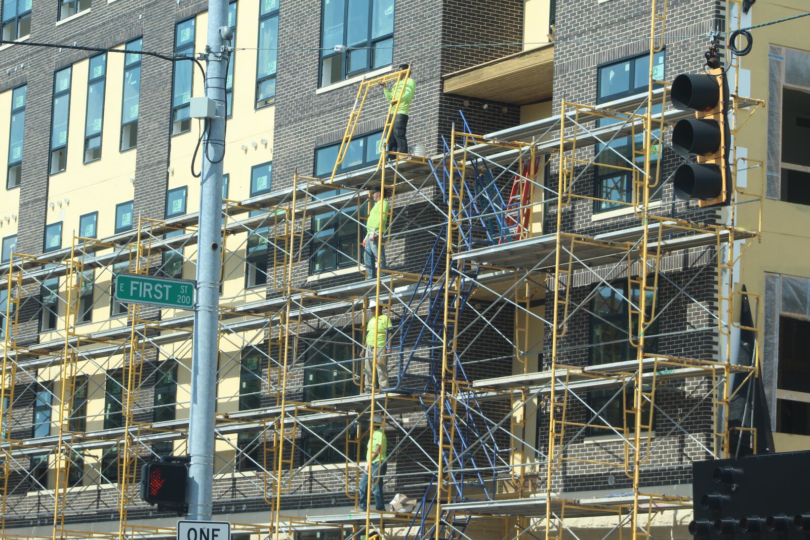 Construction crews work on the exterior of a new apartment building in downtown Dayton called the Sutton. CORNELIUS FROLIK / STAFF