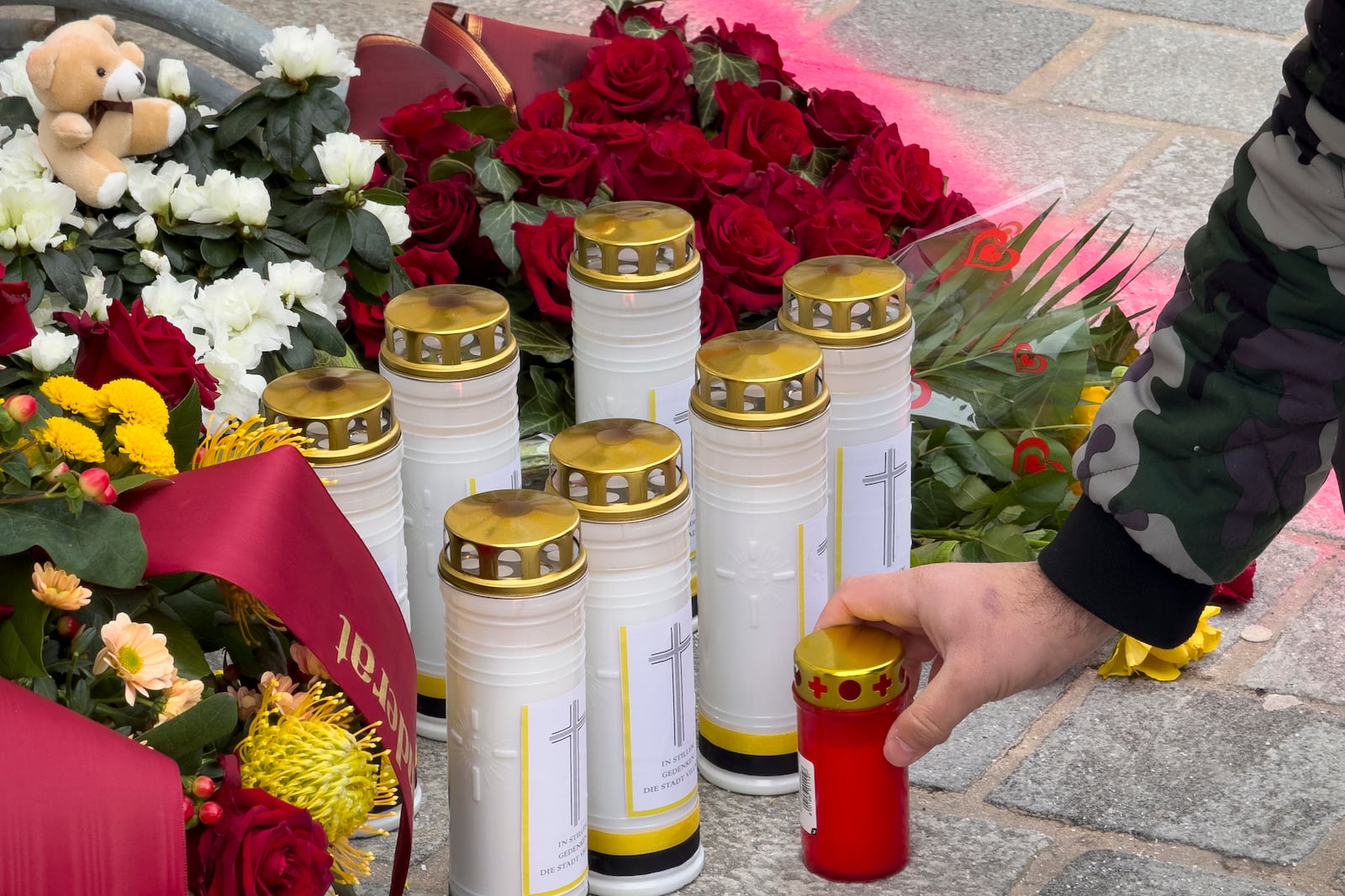 A man lights a candle at the site of stabbing a day after an attack that left a 14-year-old dead and five others injured, in Villach, Austria, Sunday, Feb. 16, 2025. (AP Photo/Darko Bandic)